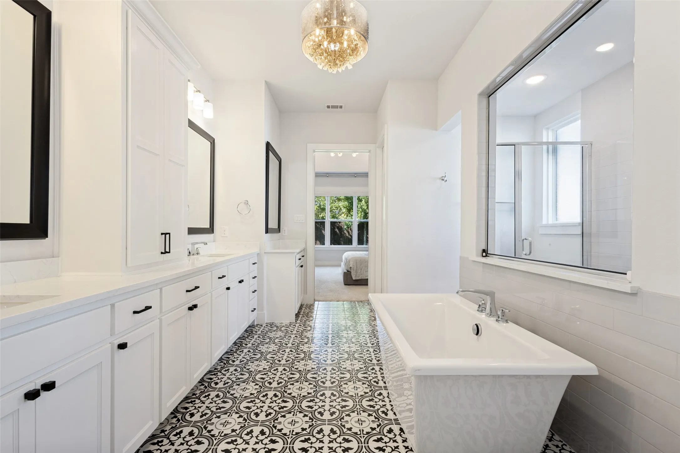 Dual vanity with white cabinetry, pattern tile flooring, freestanding bathtub, and a built-in shower enclosure