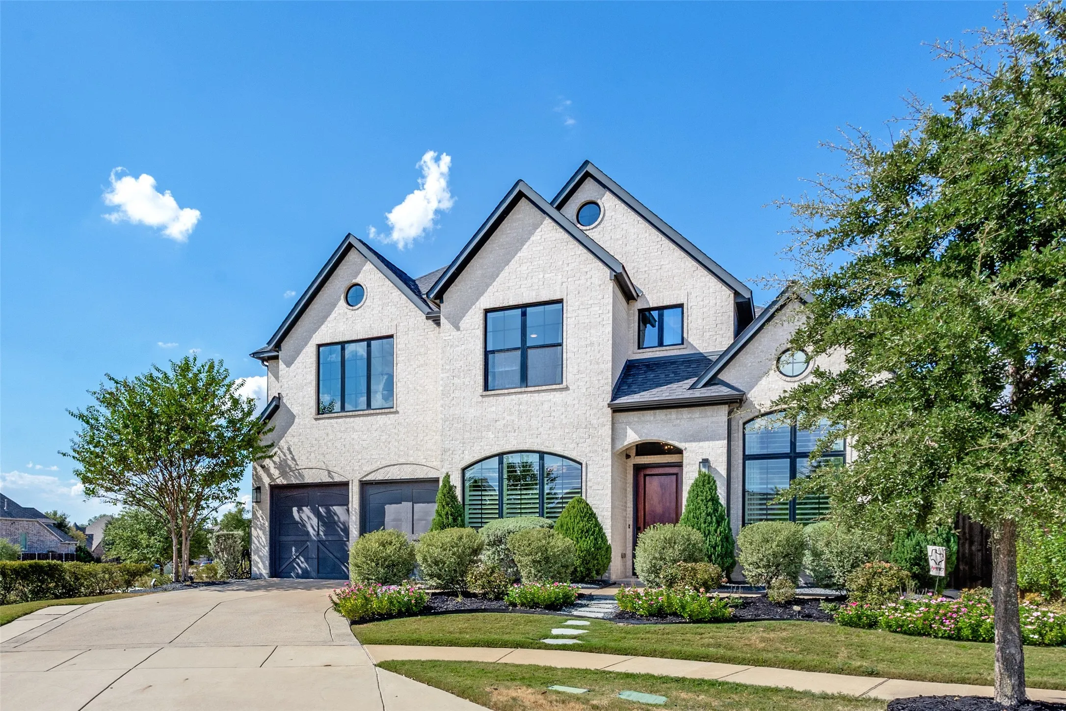 Stone exterior with black-framed windows, a dark wood entry door, and a two-car garage with dark wood-finish doors