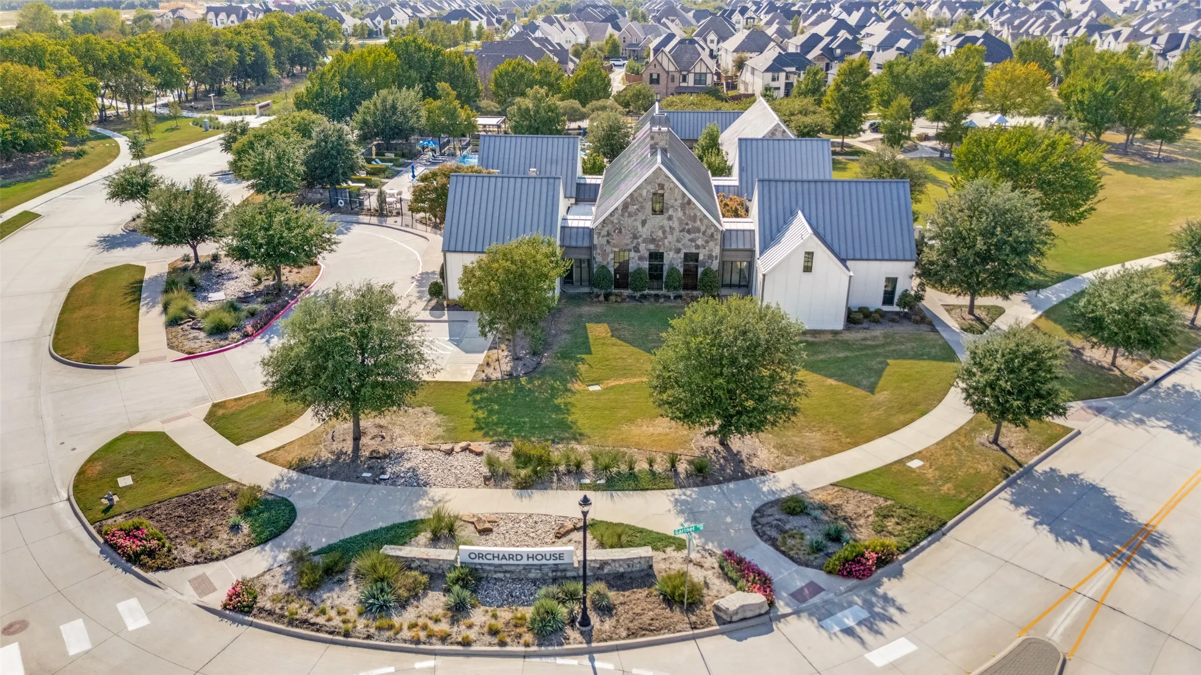 Modern farmhouse-style architecture with stone and vertical siding, complemented by dark metal roofing