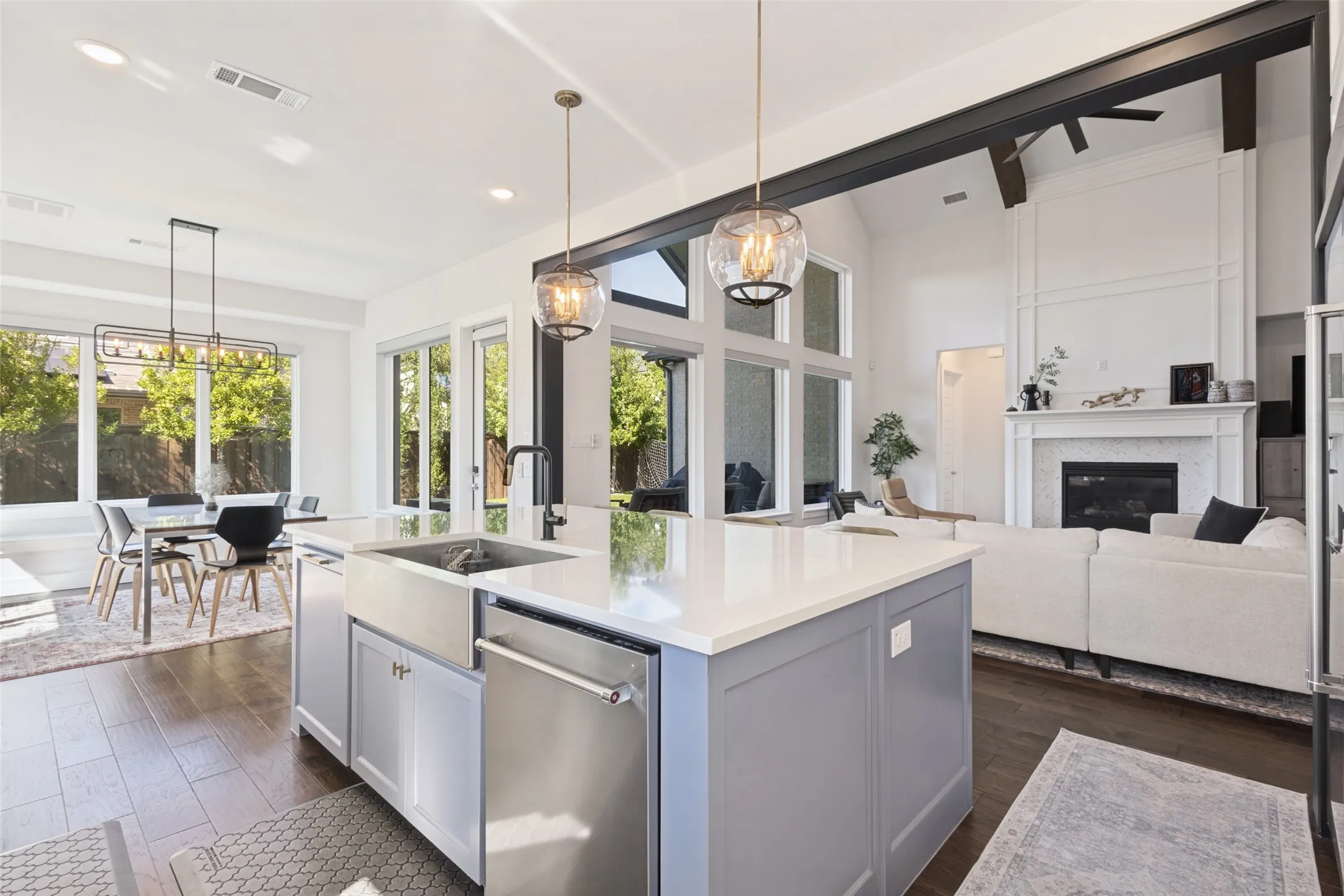 Kitchen island with farmhouse sink and integrated dishwasher, wood-finish flooring, and high ceilings with exposed beams