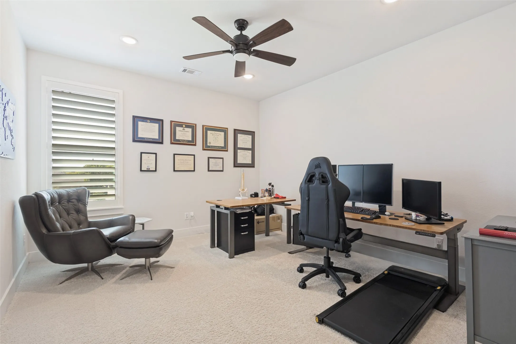 Recessed lighting, ceiling fan, white walls, carpeted flooring, and a window with plantation shutters
