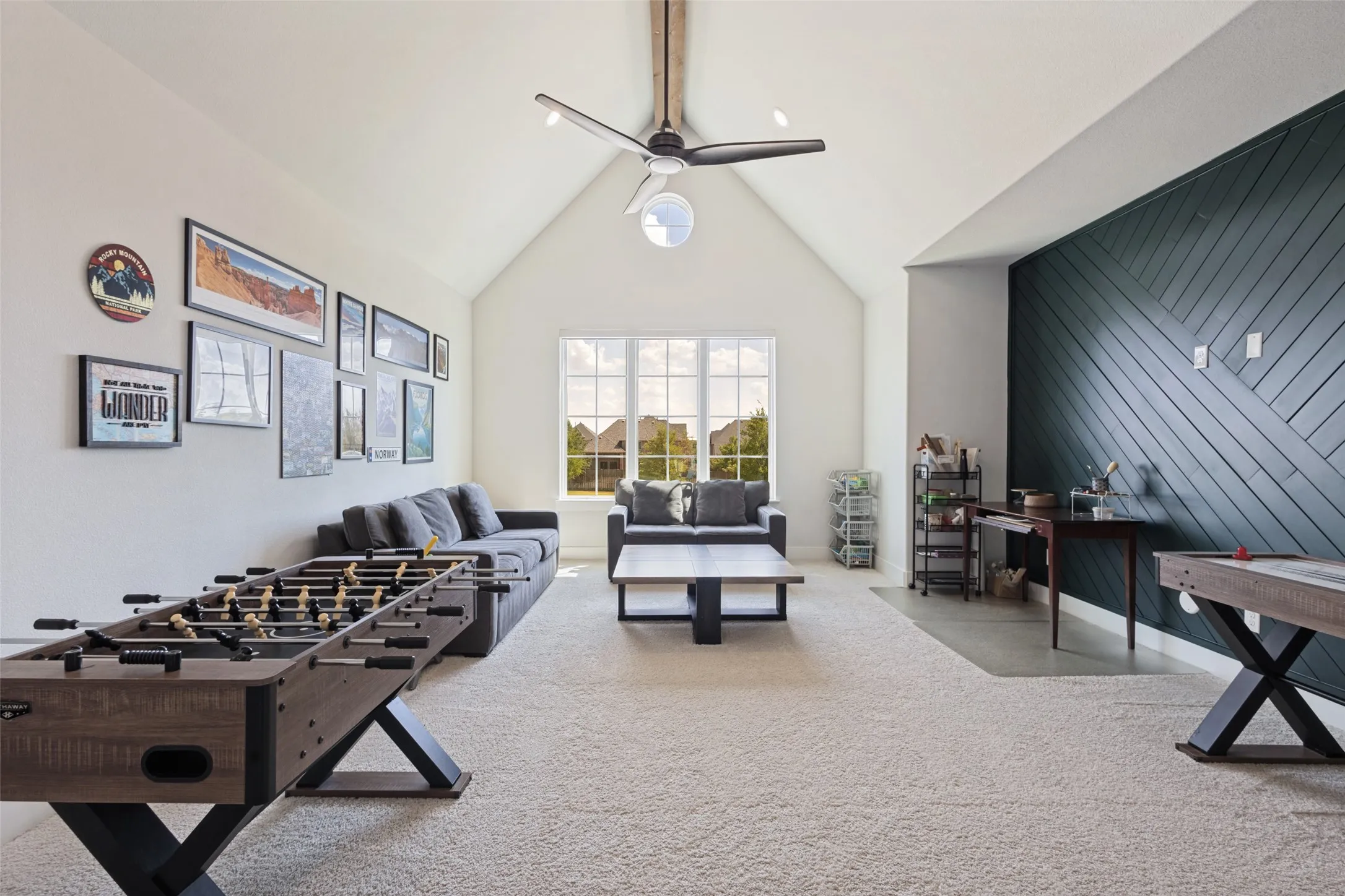 Spacious living area featuring a vaulted ceiling, ceiling fan, and carpeted flooring
