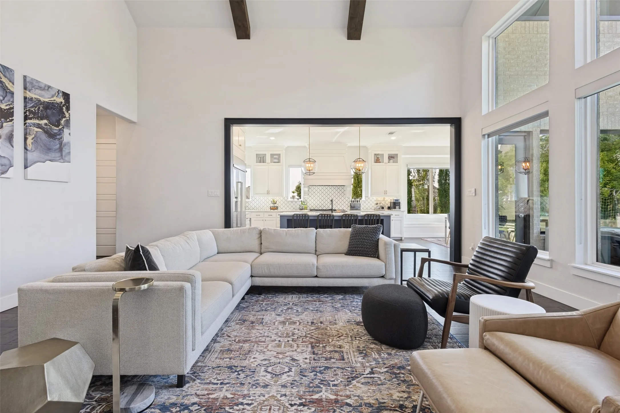 Vaulted ceilings with exposed beams, dark wood-finish flooring, and expansive windows