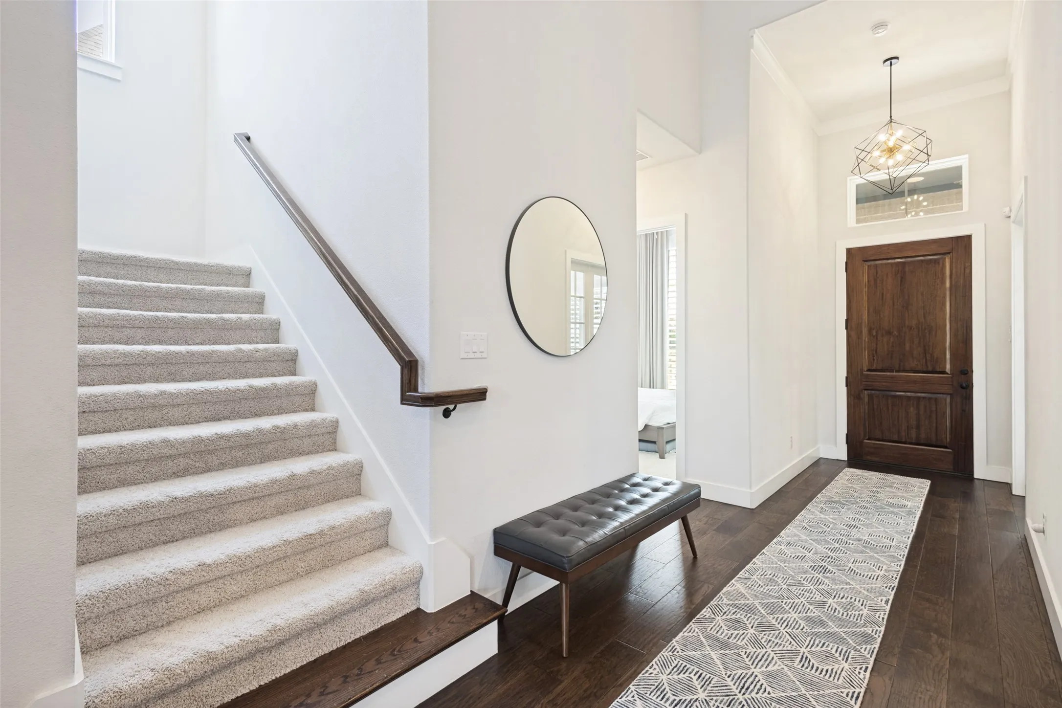 Entryway with a dark wood-paneled door, transom window, and a geometric pendant light fixture