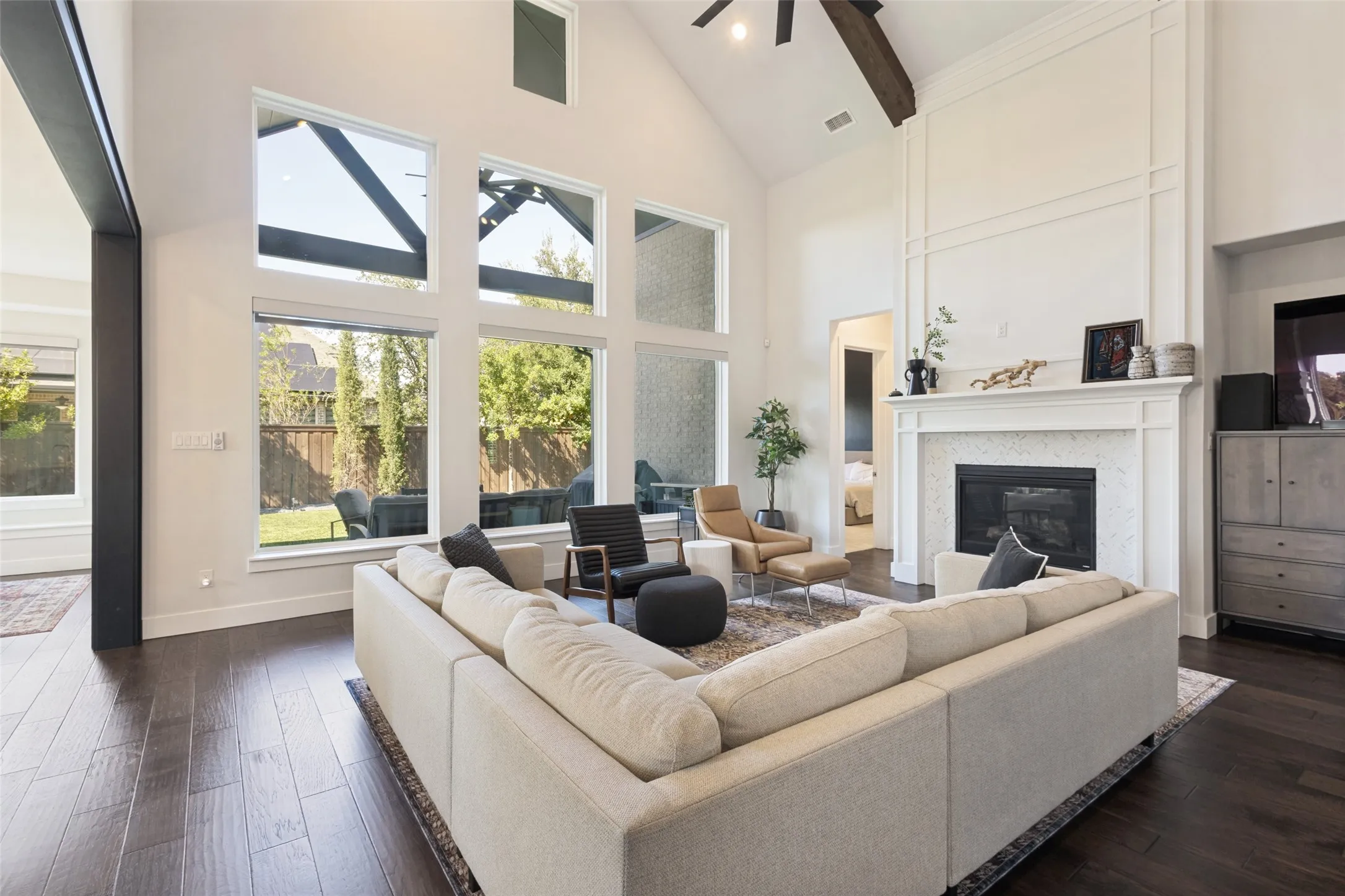 Vaulted ceilings with exposed wood beam, dark wood-finish flooring, and a fireplace with a white mantel and tile surround
