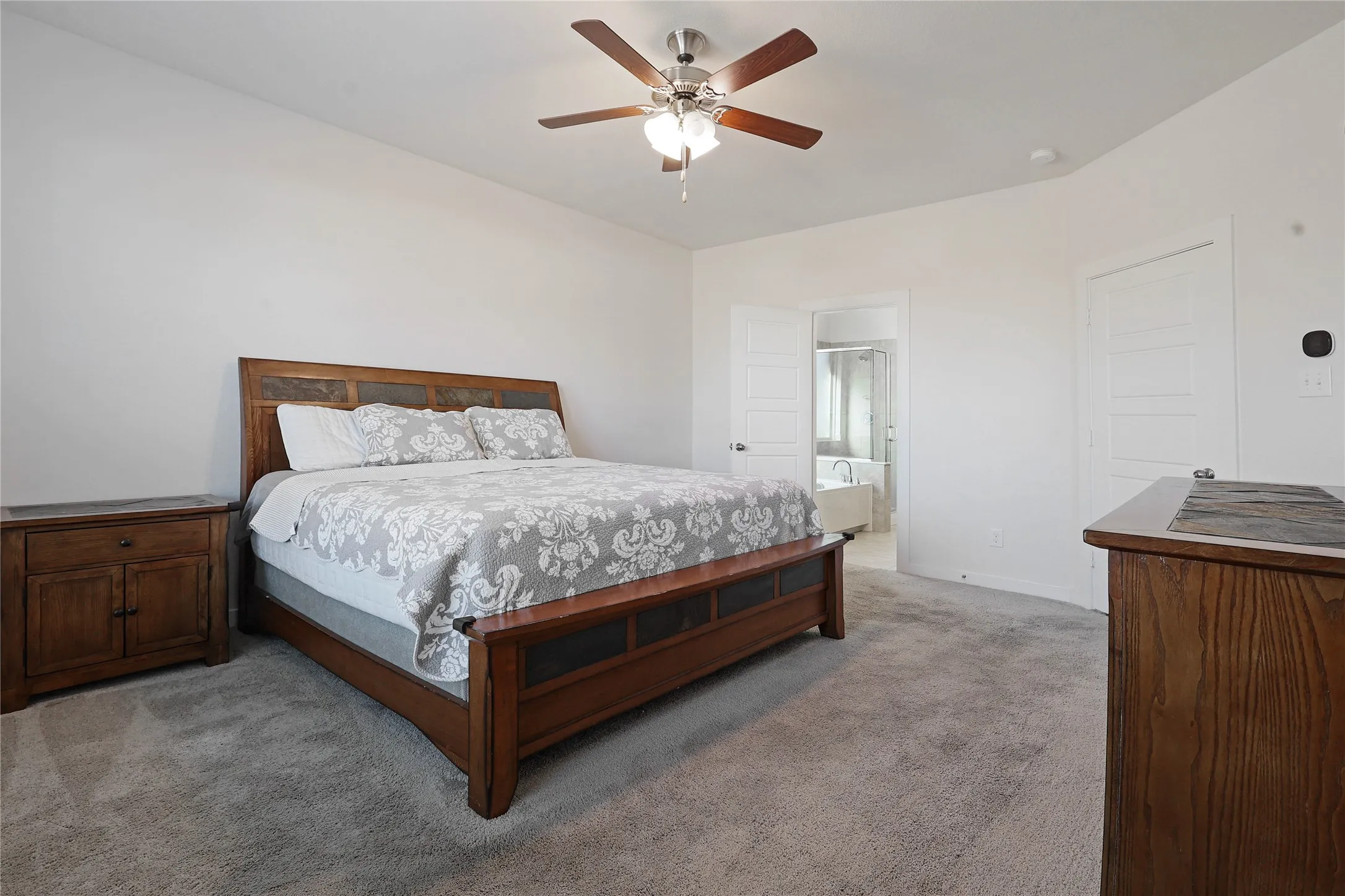 Plush carpet flooring, ceiling fan with integrated lighting, and a white interior door