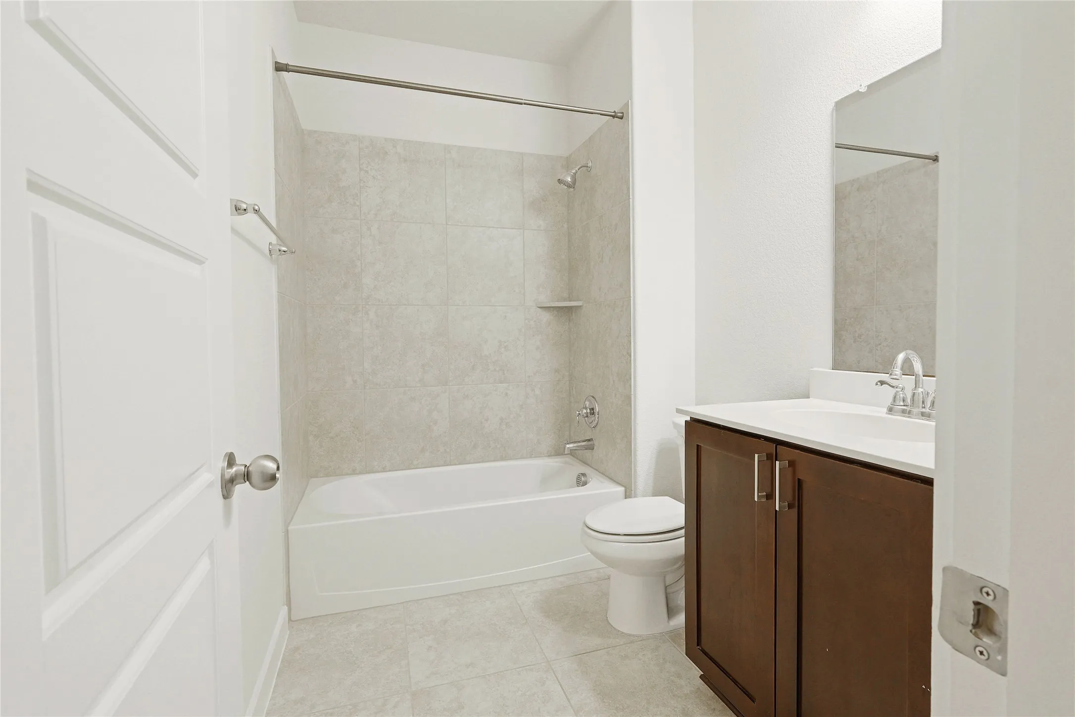 Full bathroom featuring a single vanity with wood-finish cabinetry, white countertop, and tiled flooring