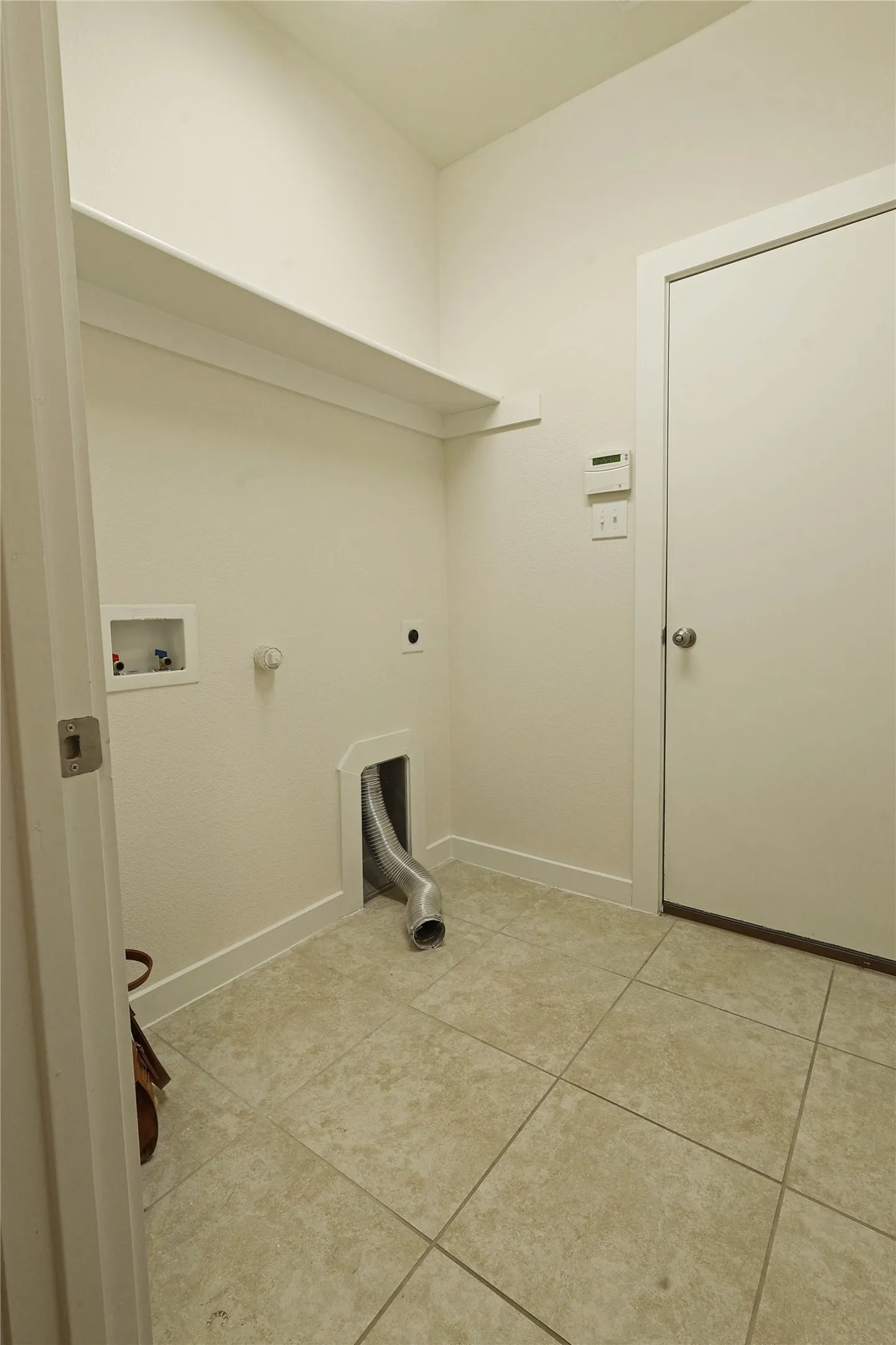 Laundry area featuring a tiled floor, built-in shelving, and utility hookups