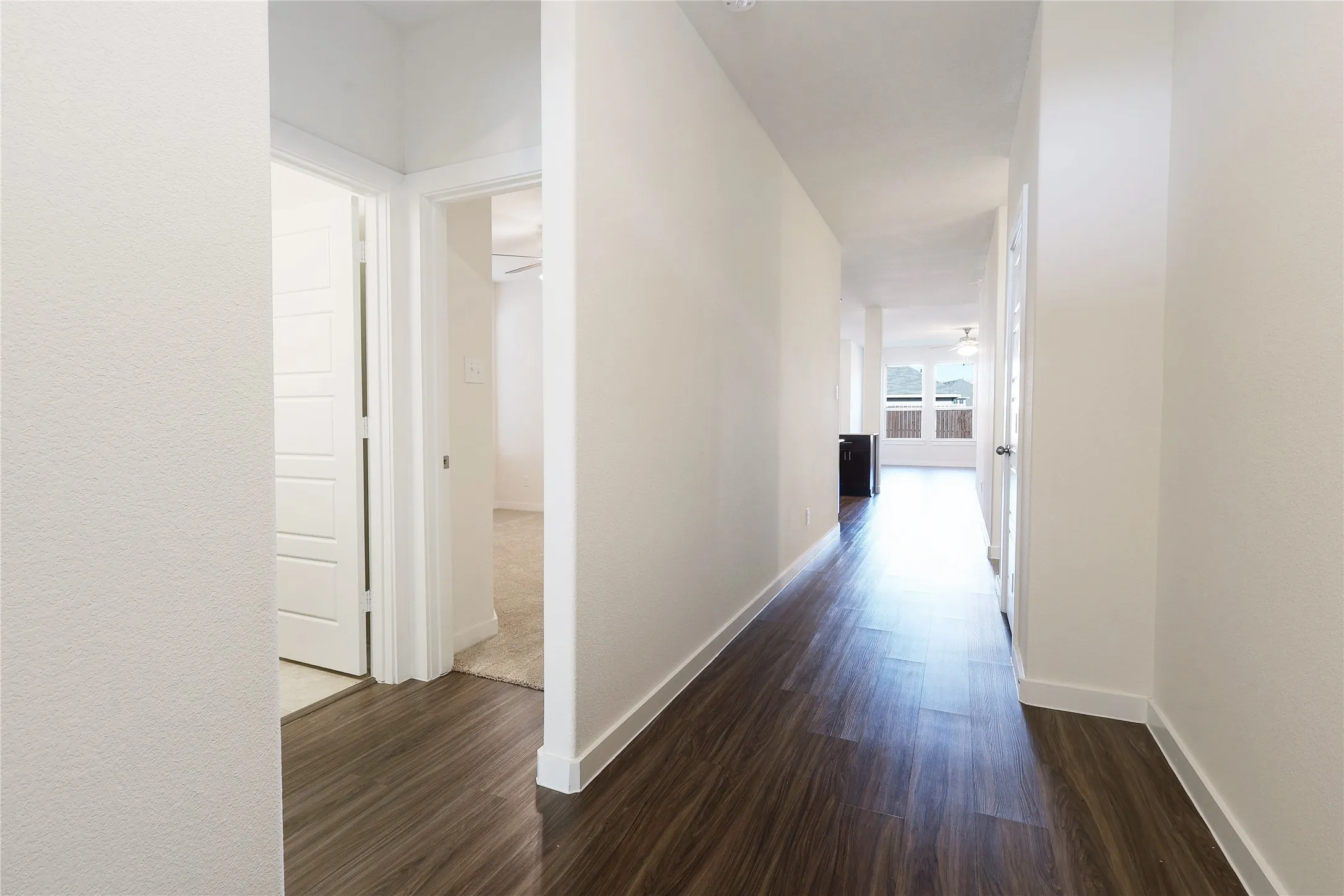 Hallway with wood-finish flooring, white walls, and white trim