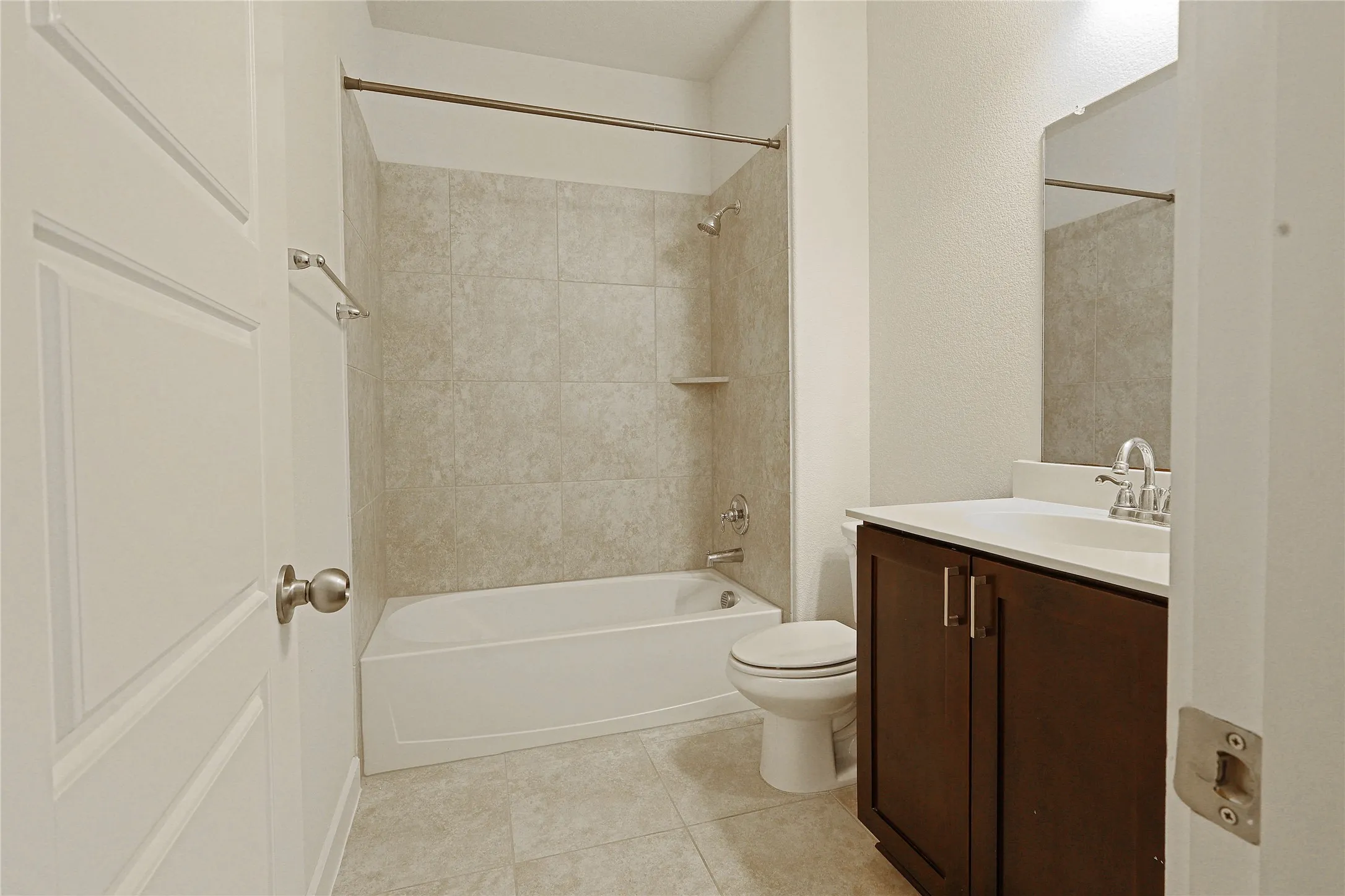 Spacious bathroom with a full-size tub, integrated shower, tile surround, and a vanity with a dark wood-finish cabinet