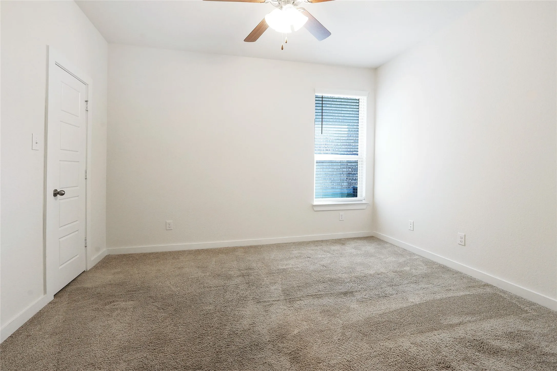 Neutral-toned carpeting, white walls, and a window with blinds