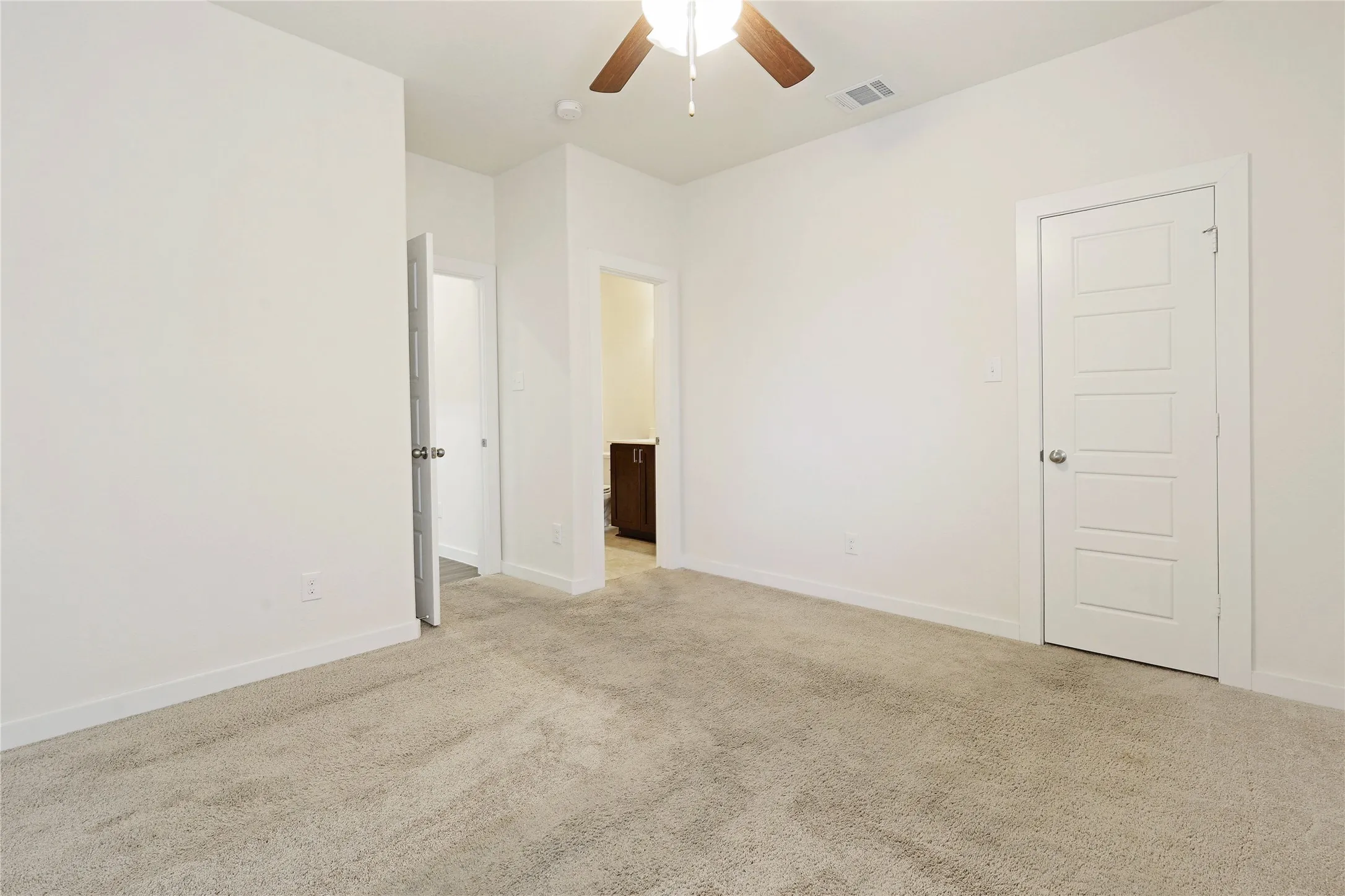 Neutral tone wall paint, carpeted flooring, white trim, and a ceiling fan with integrated lighting