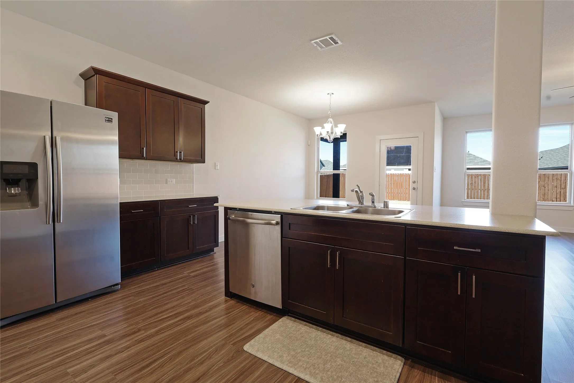 Kitchen featuring wood-finish flooring, dark wood cabinetry, stainless steel appliances, and a white subway tile backsplash