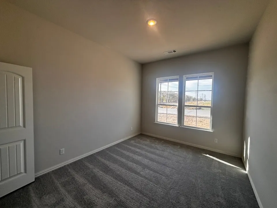 Neutral wall paint, patterned carpet flooring, recessed ceiling light, white trim windows, and a panel door