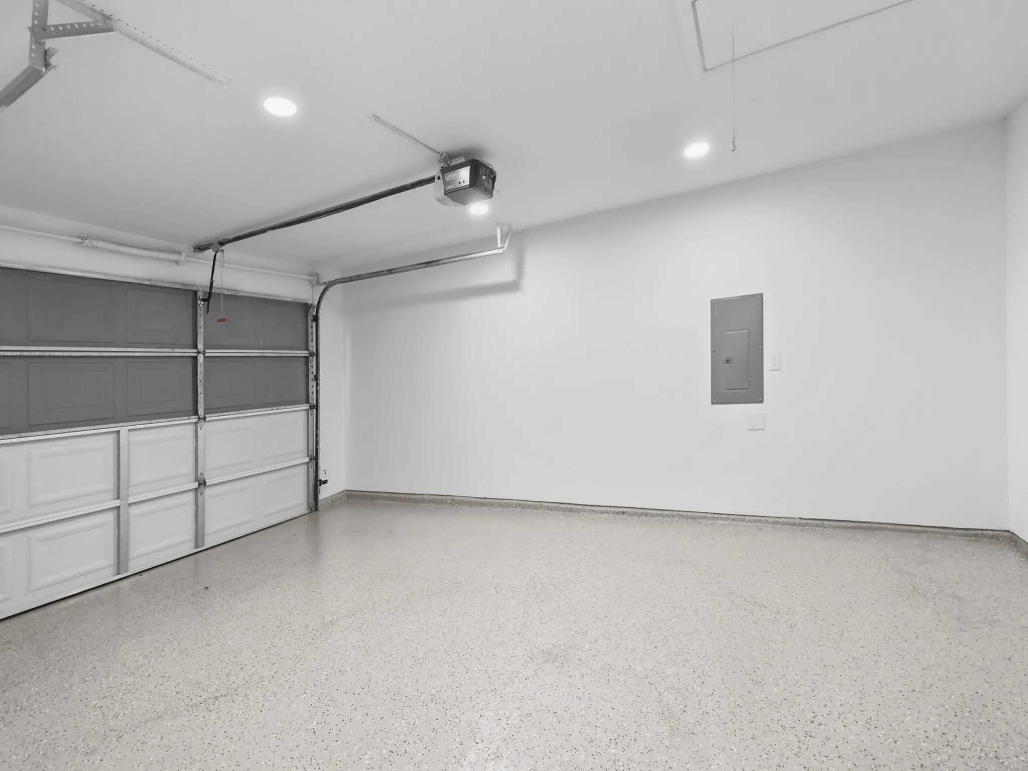 Spacious garage with an automatic overhead door, recessed ceiling lighting, and a durable epoxy-coated concrete floor