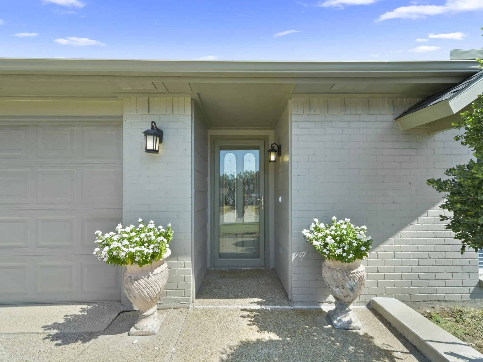 Painted brick exterior with a paneled garage door and a clear-paneled entry door