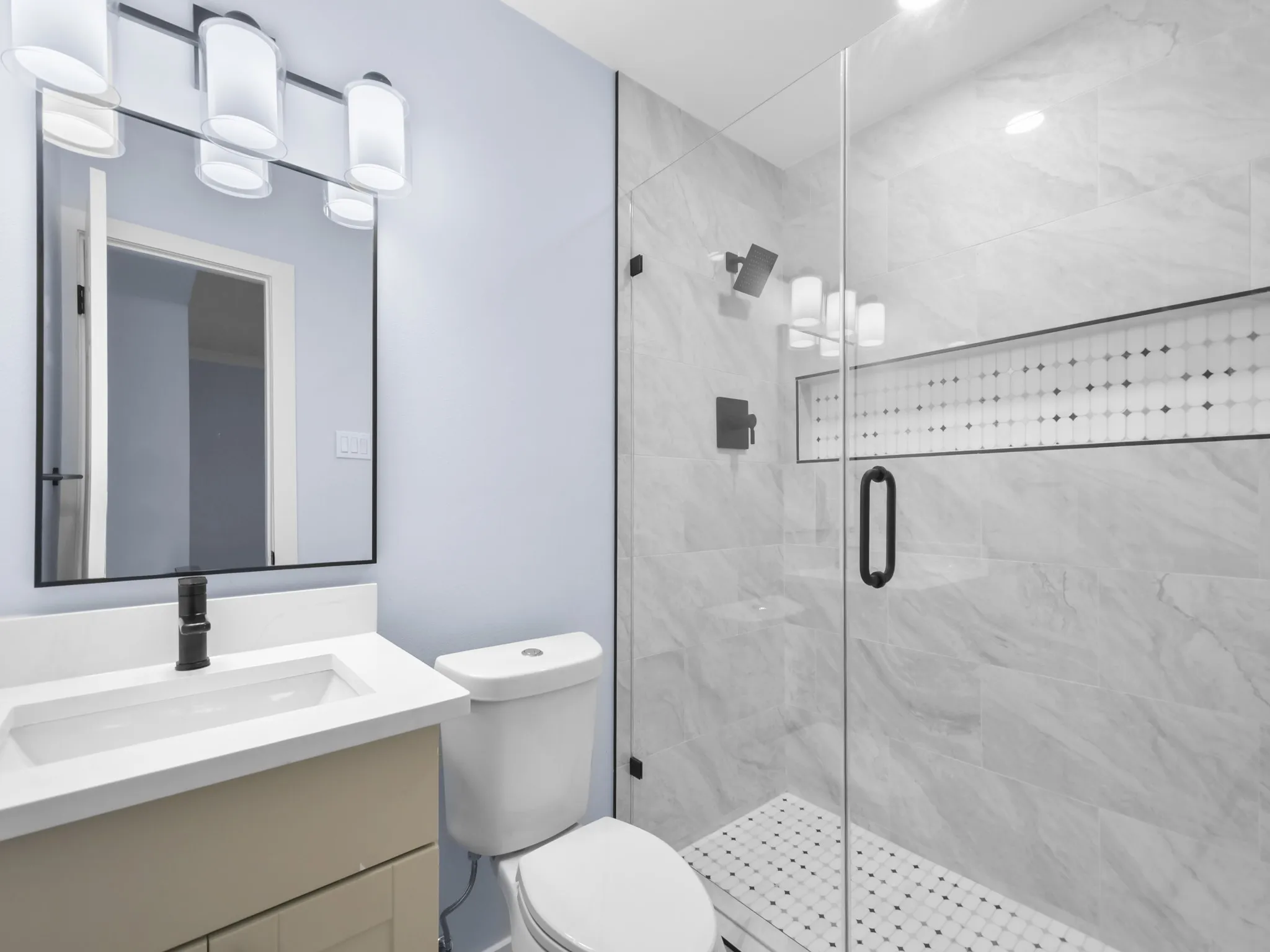 Glass-enclosed shower with a tiled niche and mosaic-tiled floor