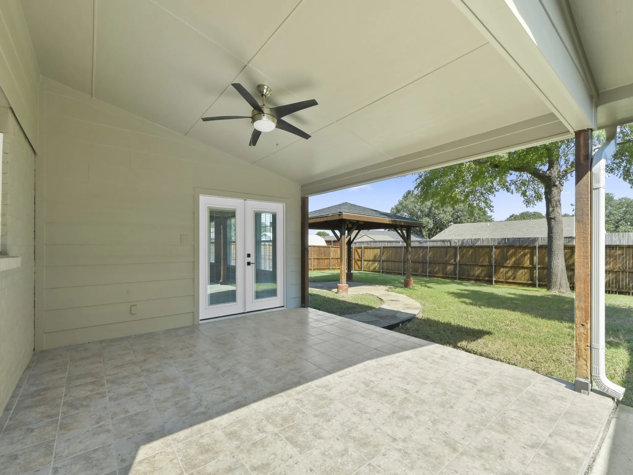 Covered patio with a vaulted ceiling, ceiling fan, and tiled flooring