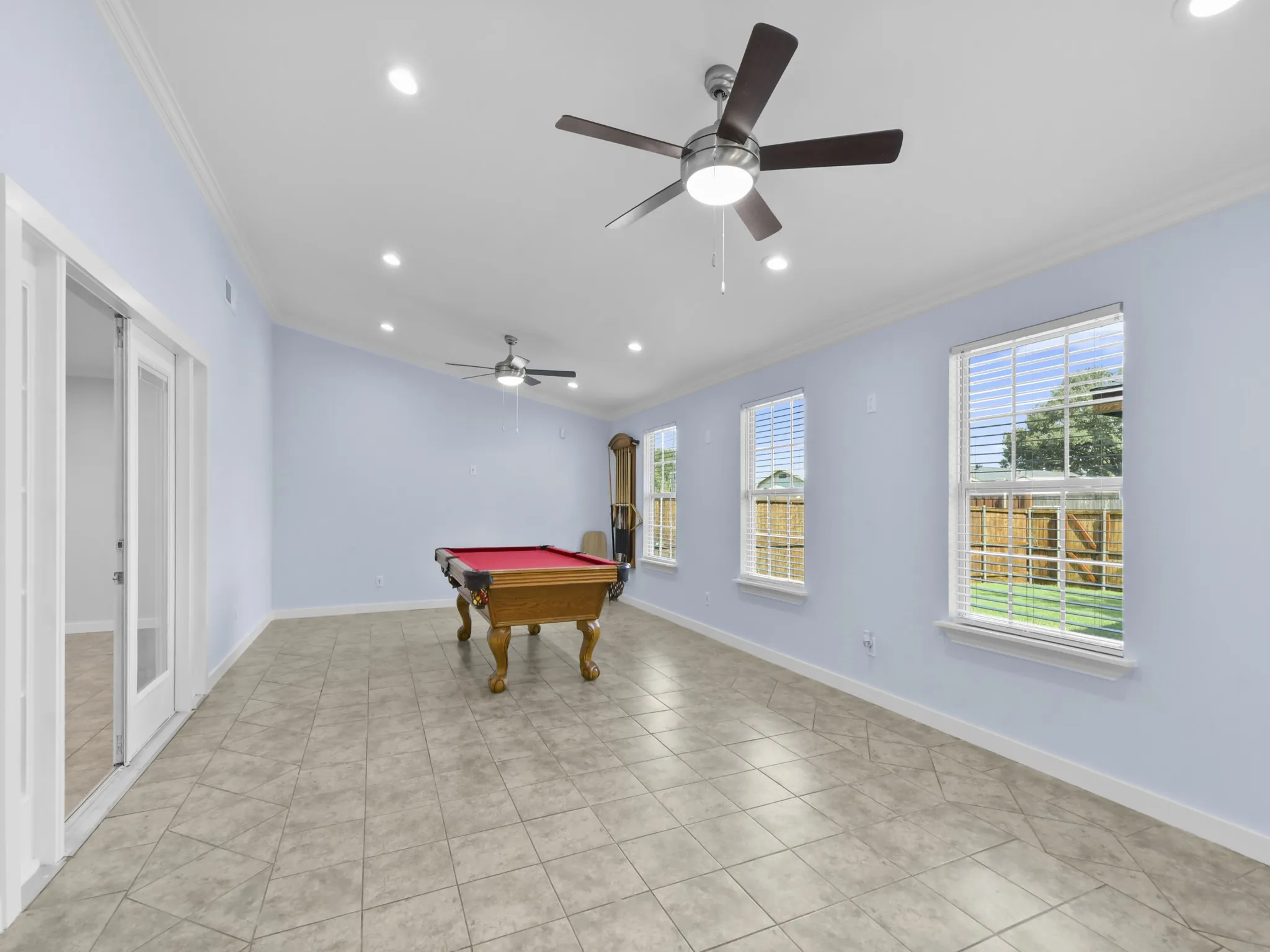 Spacious room featuring tile flooring, multiple windows with blinds, recessed lighting, and dual ceiling fans