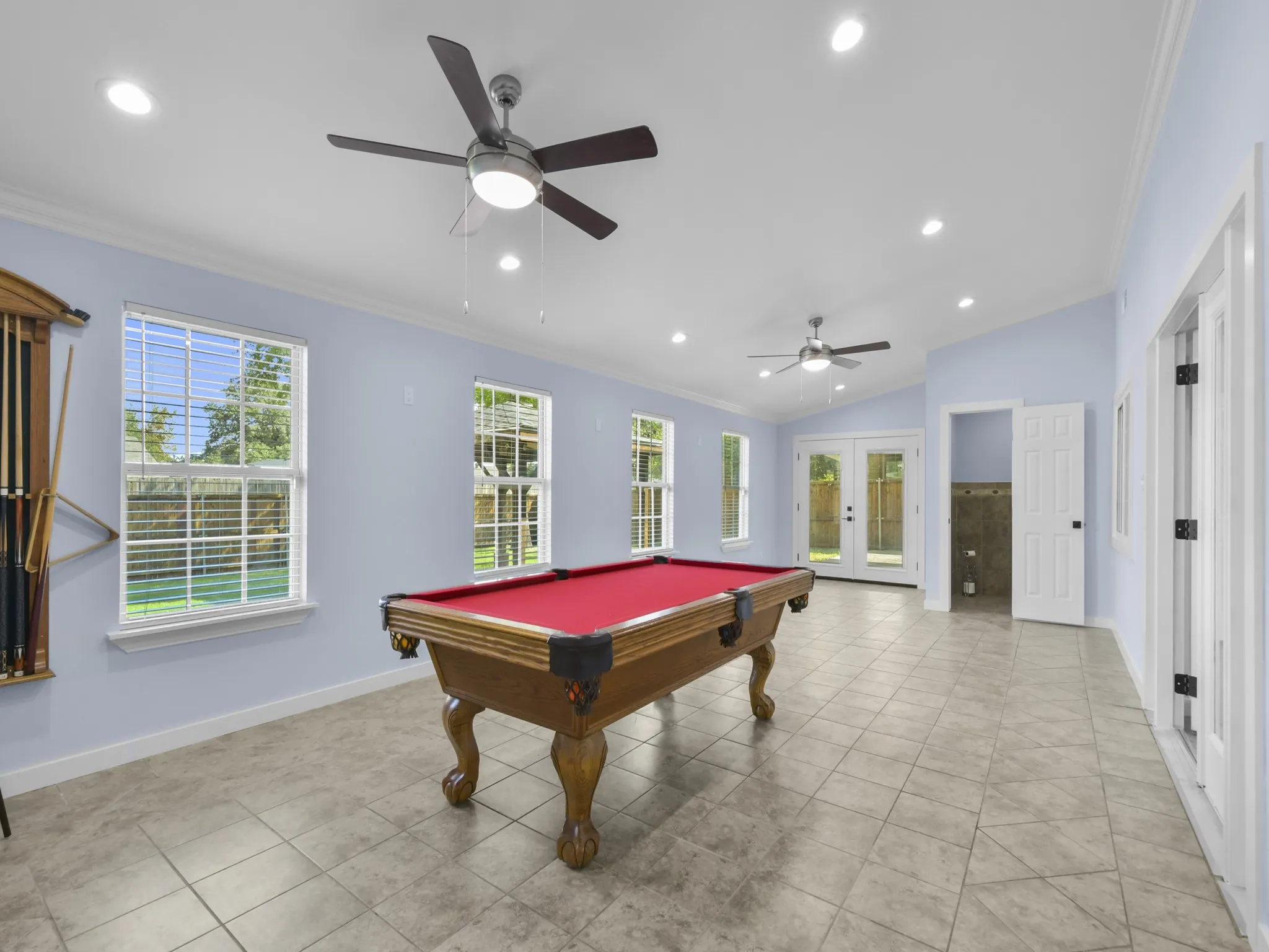 Spacious room with vaulted ceilings, recessed lighting, ceiling fans, multiple windows, and tile flooring