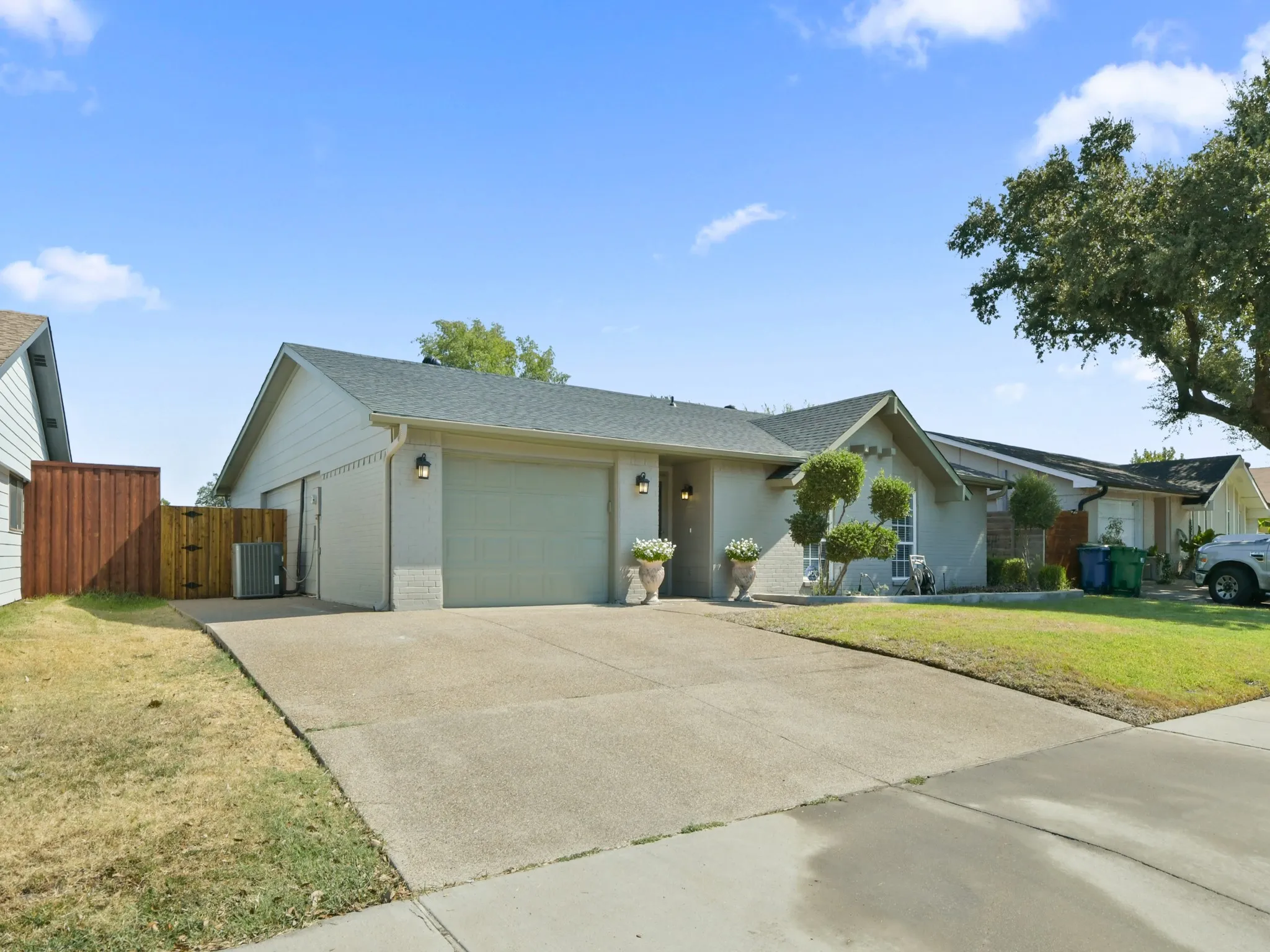 Single-story residence featuring an attached garage, concrete driveway, and a wood privacy fence