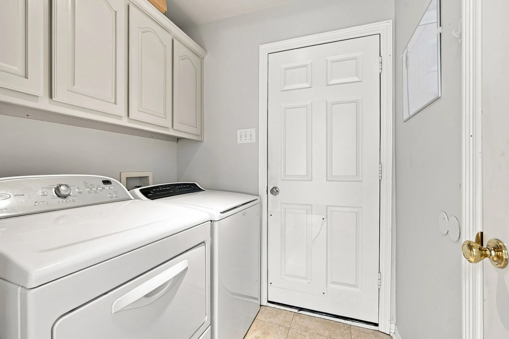 This utility room is equipped with built-in cabinets and a storage closet for organizational needs