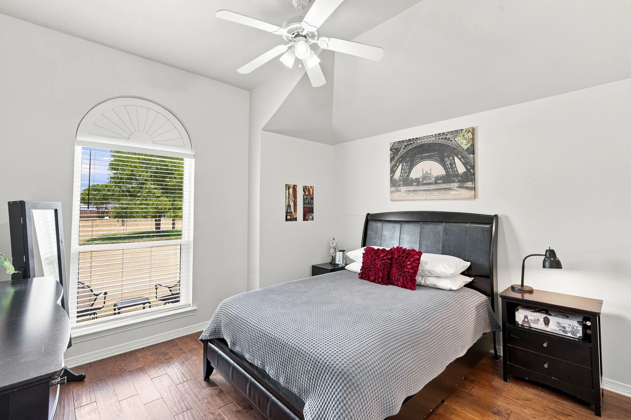 Space is bountiful in the primary suite featuring a vaulted ceiling, blinds, and ceiling fan