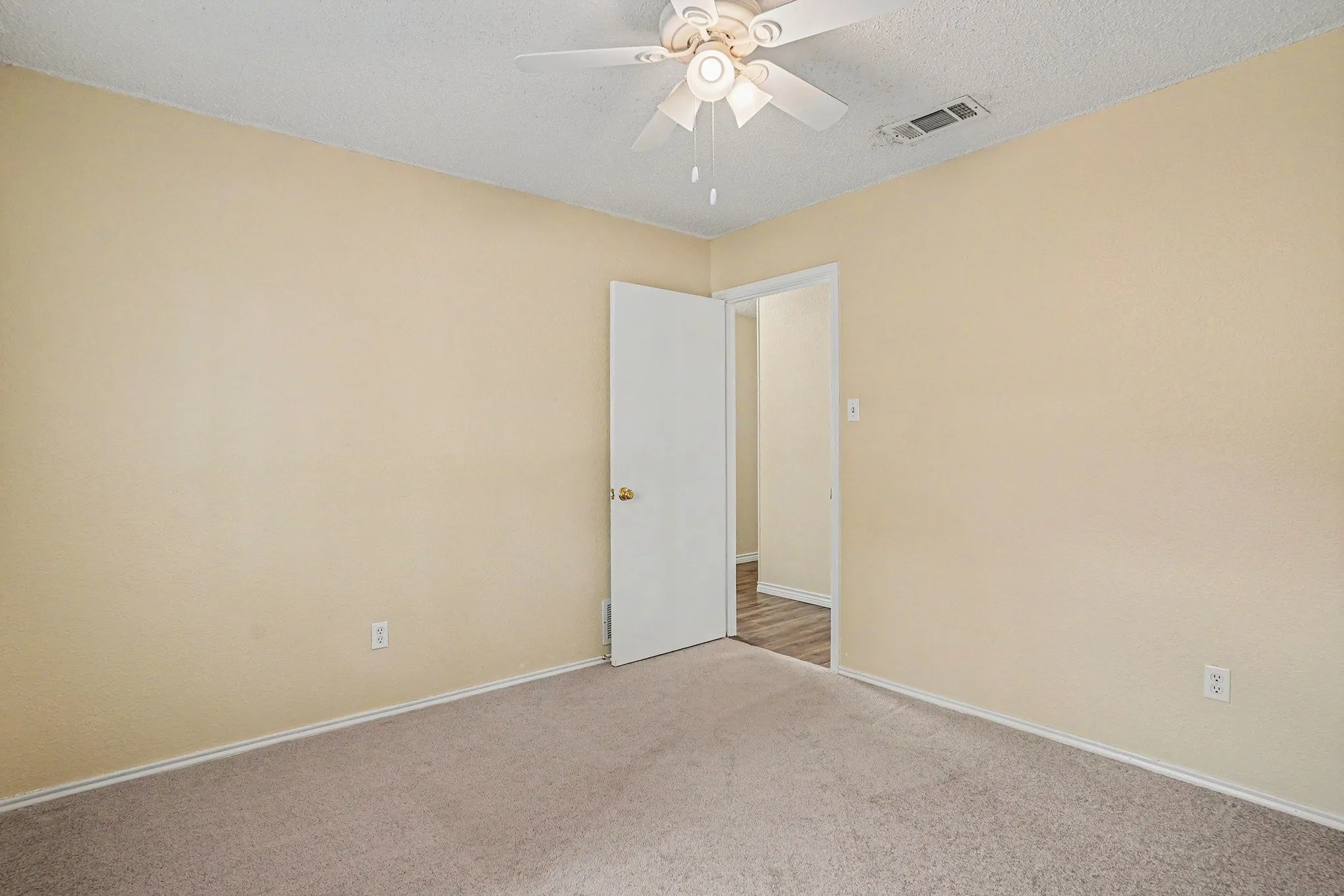 Neutral wall finishes, textured ceiling, ceiling fan with integrated lighting, and carpet flooring