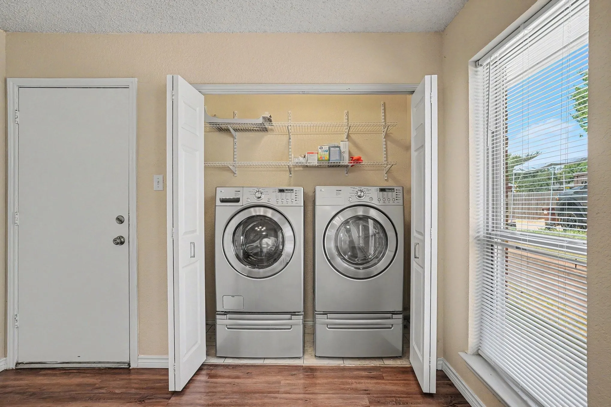 Laundry closet with bi-fold doors, wire shelving, and wood-finish flooring