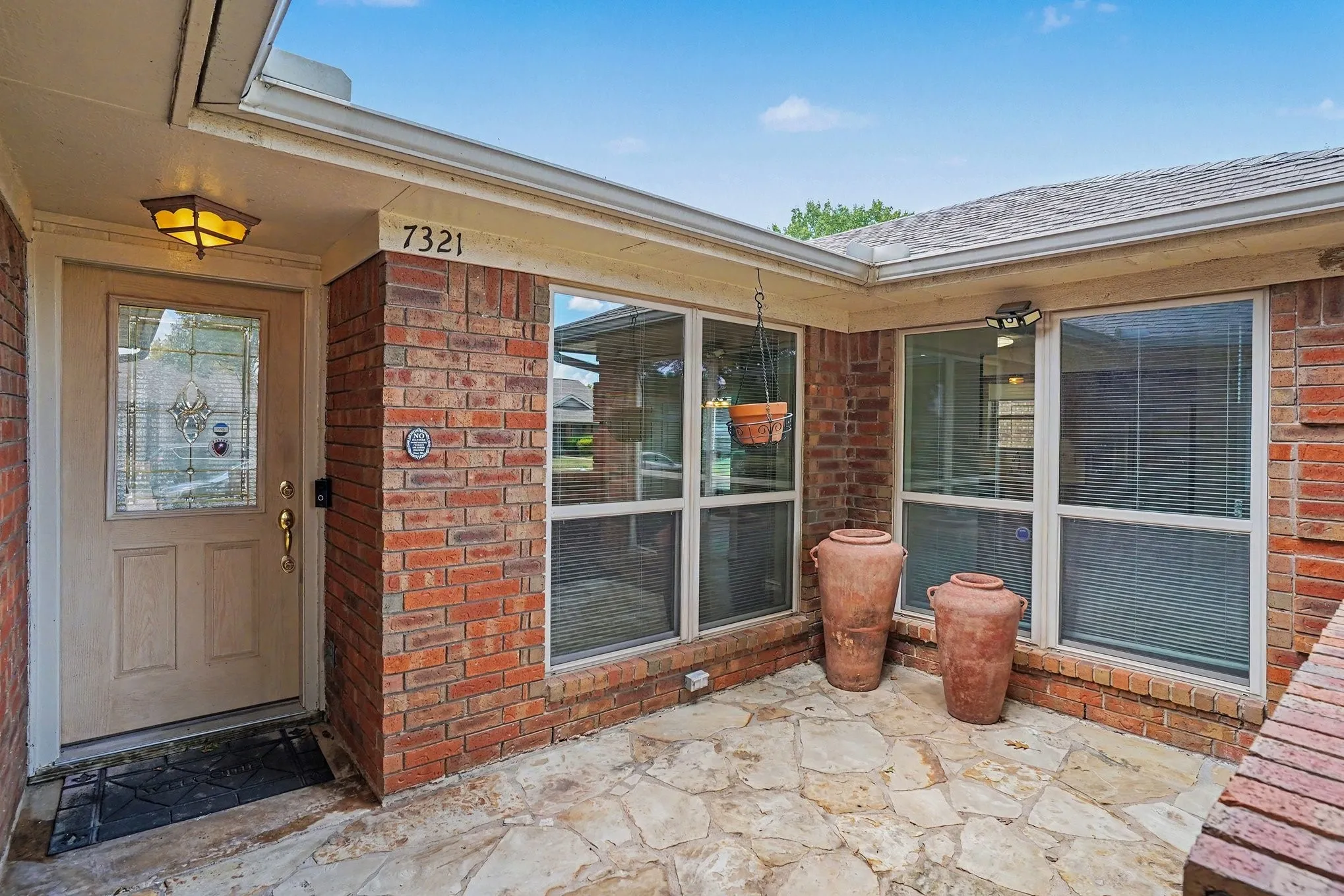 Brick exterior facade with a covered entry, decorative glass front door, and flagstone entryway