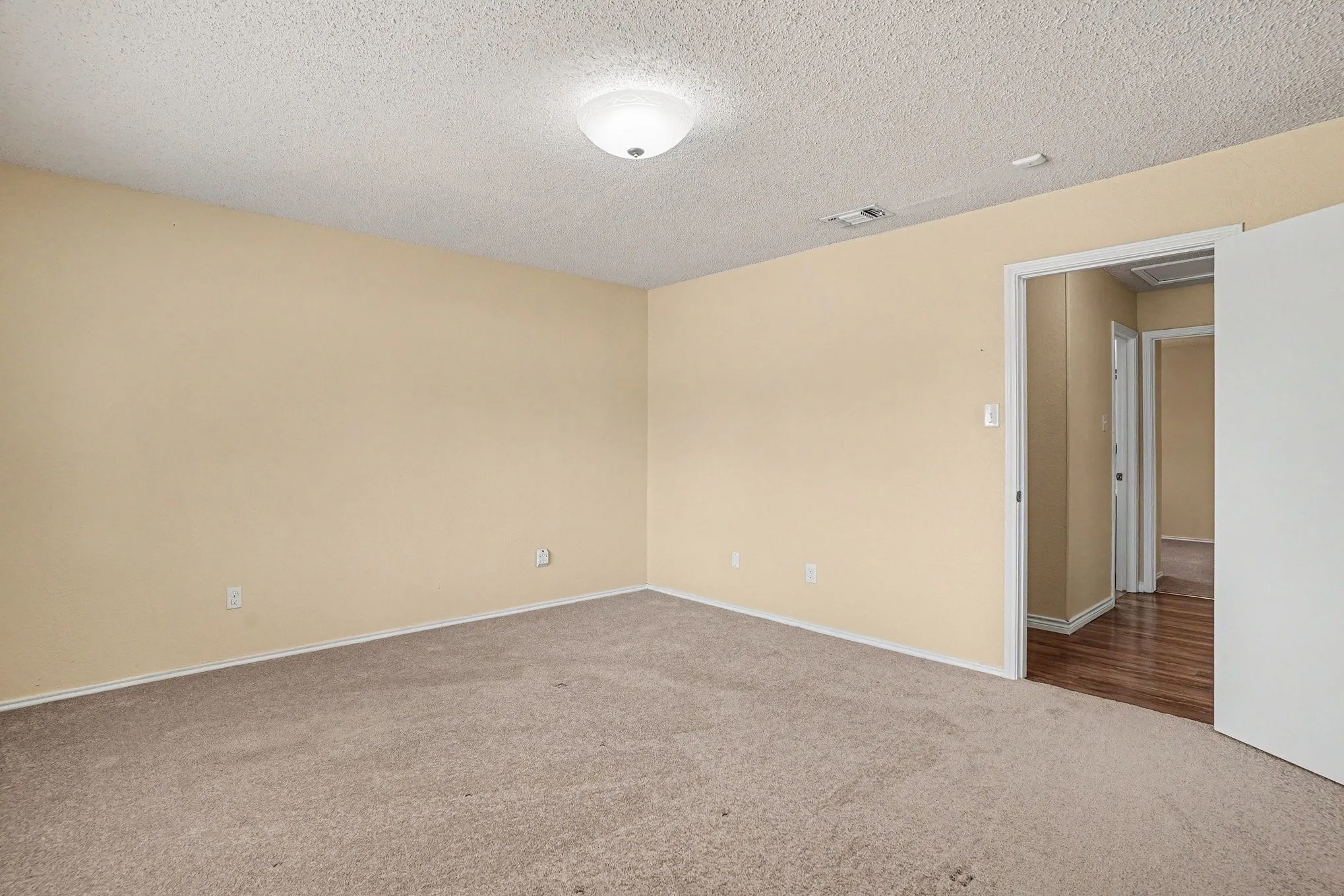 Carpeted room featuring light-colored walls and a flush-mount ceiling light