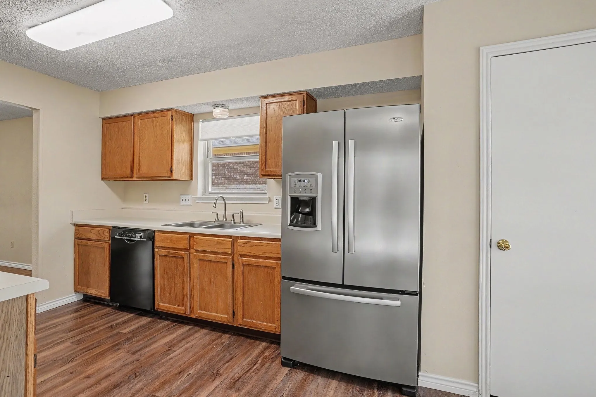 Kitchen featuring wood-finish flooring, wood cabinetry, white countertops, and a stainless steel refrigerator