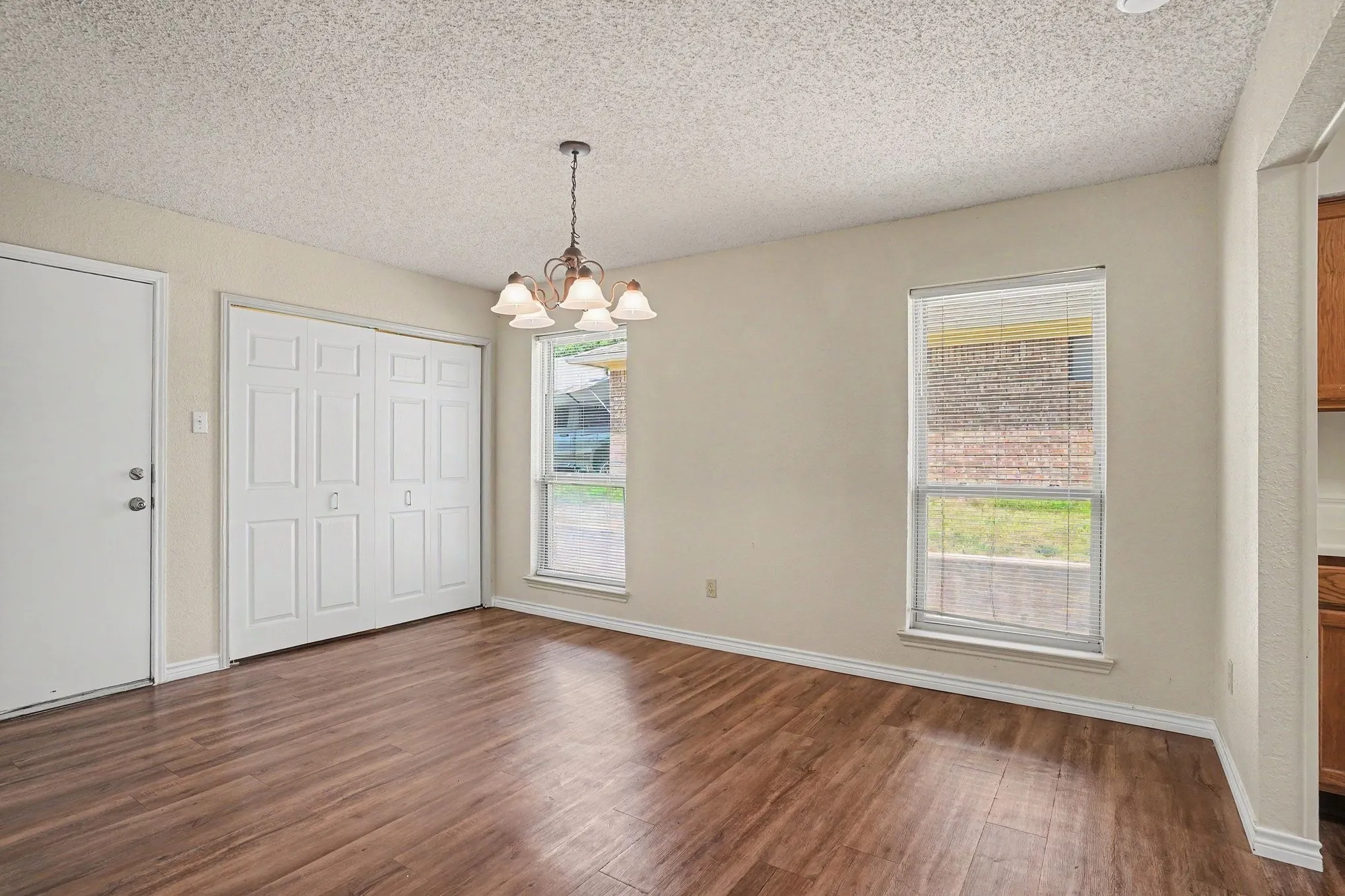 Wood-finish flooring, overhead chandelier, two windows, and bi-fold doors