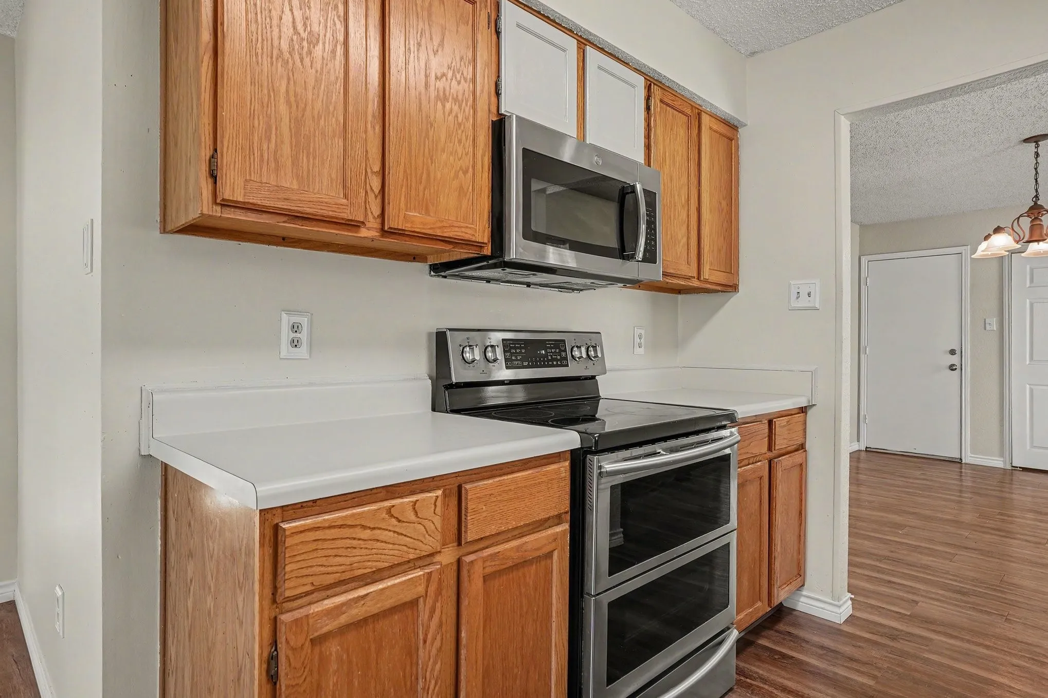 Wood-finish cabinetry paired with white countertops and stainless steel appliances