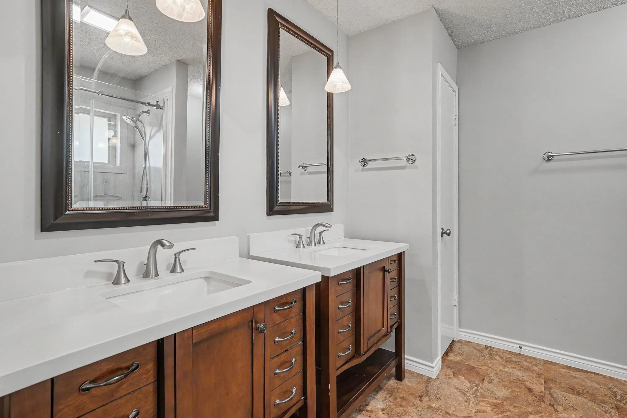 Dual wood-finish vanities with white countertops and undermount sinks