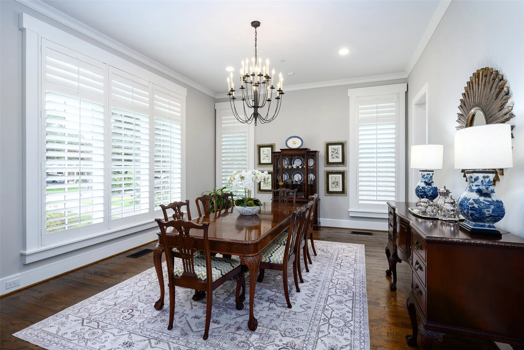 Hardwood flooring, crown molding, white plantation shutters, built-in cabinetry, and a chandelier