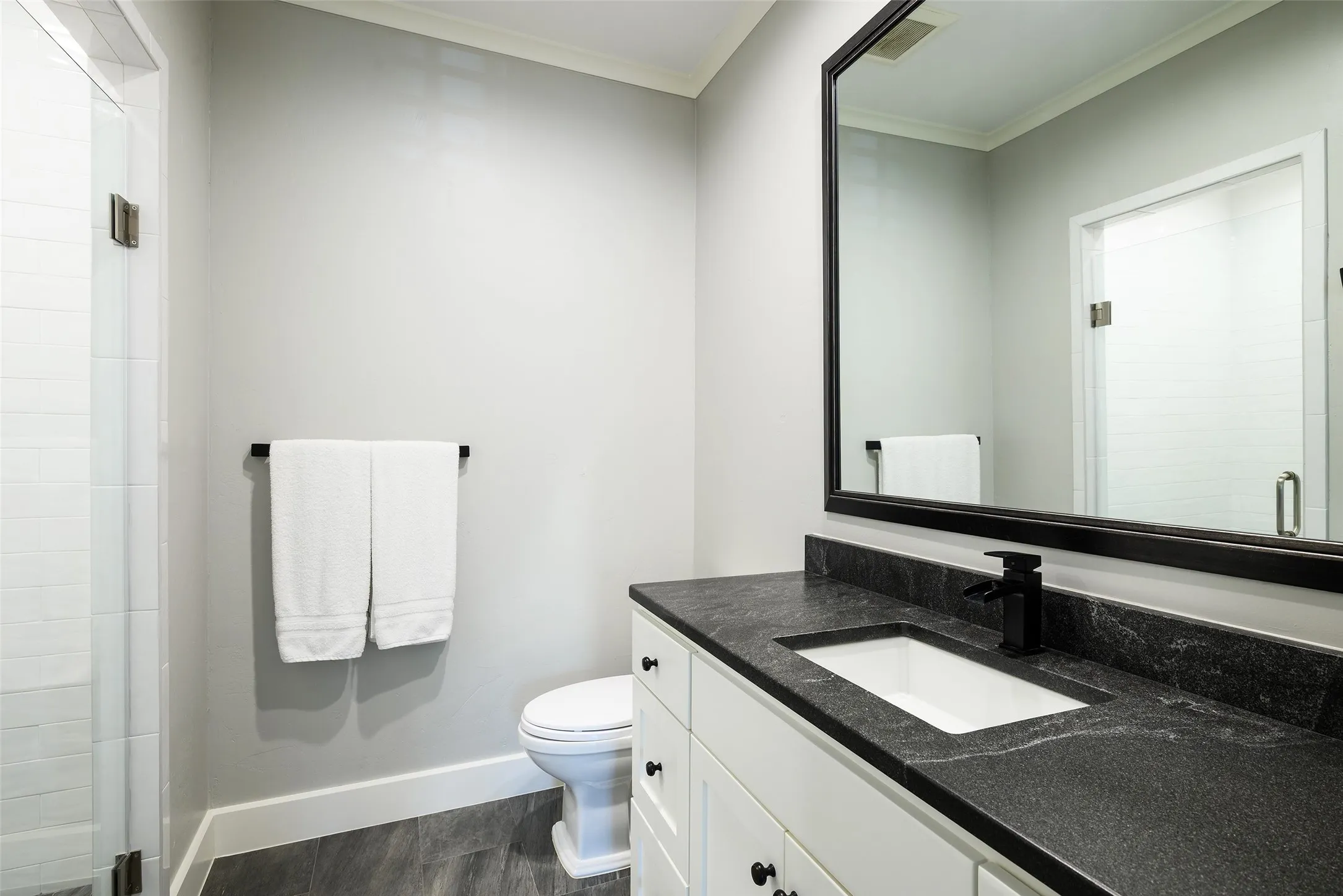Glass-enclosed shower with white tiled walls