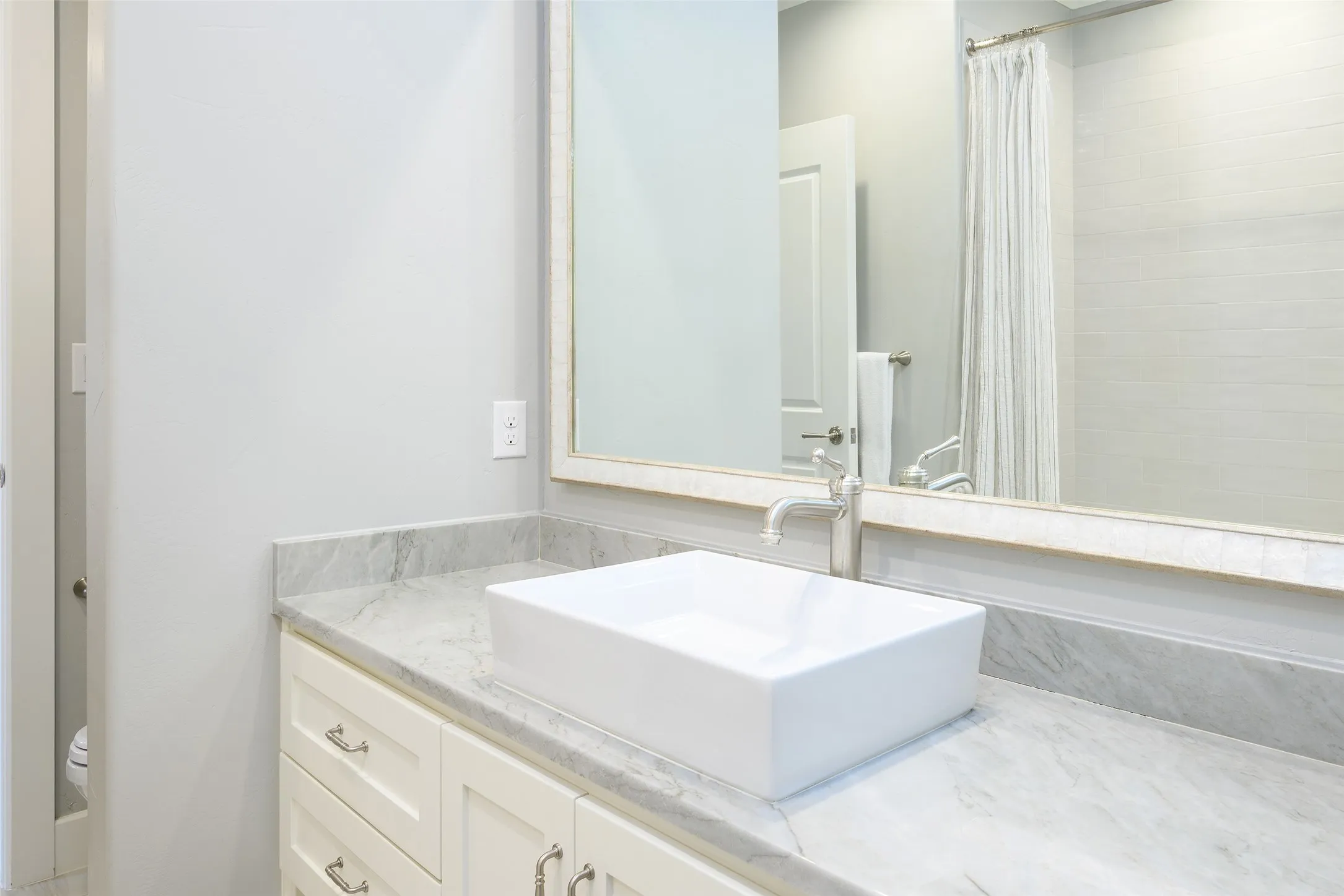 Vanity with a rectangular vessel sink, polished chrome faucet, stone countertop, and custom cabinetry