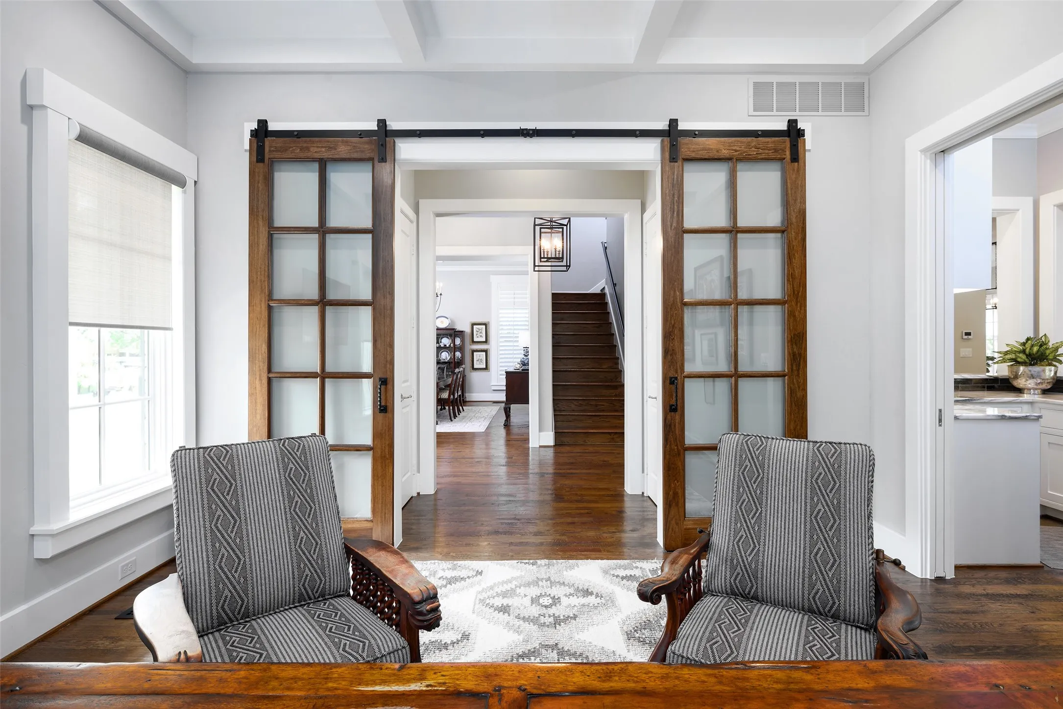 Solid wood flooring, coffered ceiling, transom window, and sliding barn doors with frosted glass panels