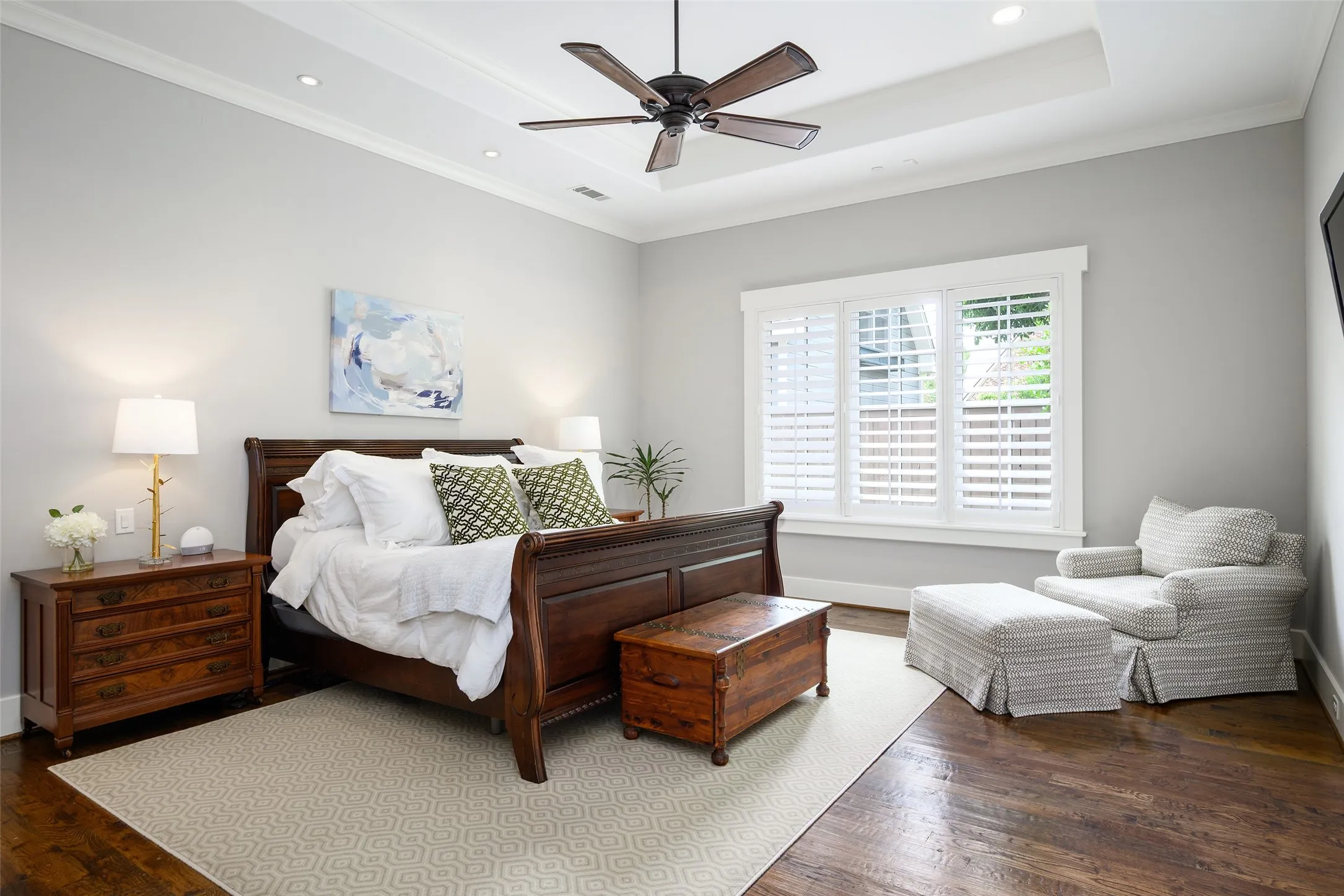 Hardwood flooring, tray ceiling with recessed lighting, ceiling fan, and plantation shutters