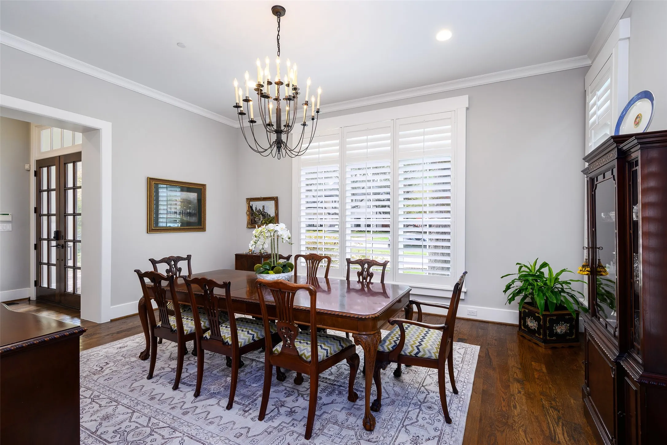 Recessed lighting, crown molding, wood-finish flooring, white window shutters, and a dark bronze chandelier