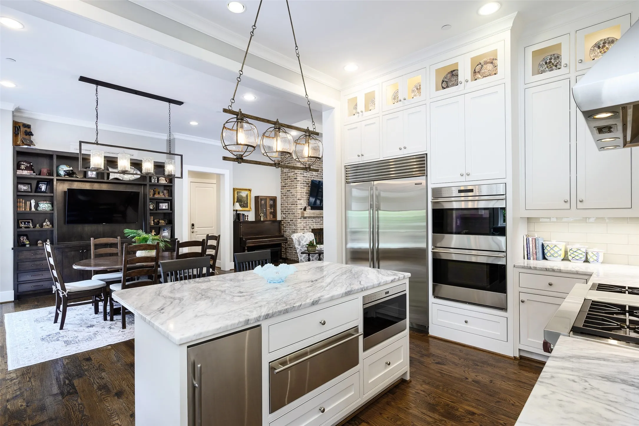 Kitchen featuring a substantial island with stone countertop, stainless steel appliances, and extensive white cabinetry