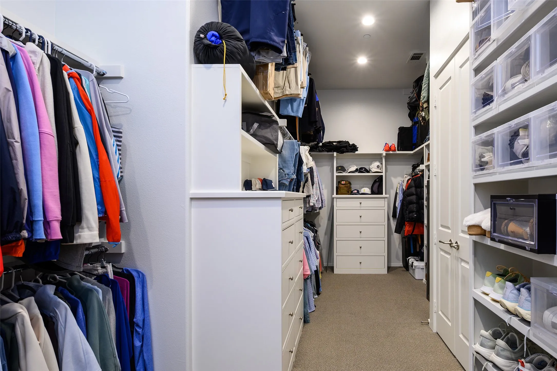 Walk-in closet featuring recessed lighting, built-in shelving, integrated drawers, and a neutral carpeted floor