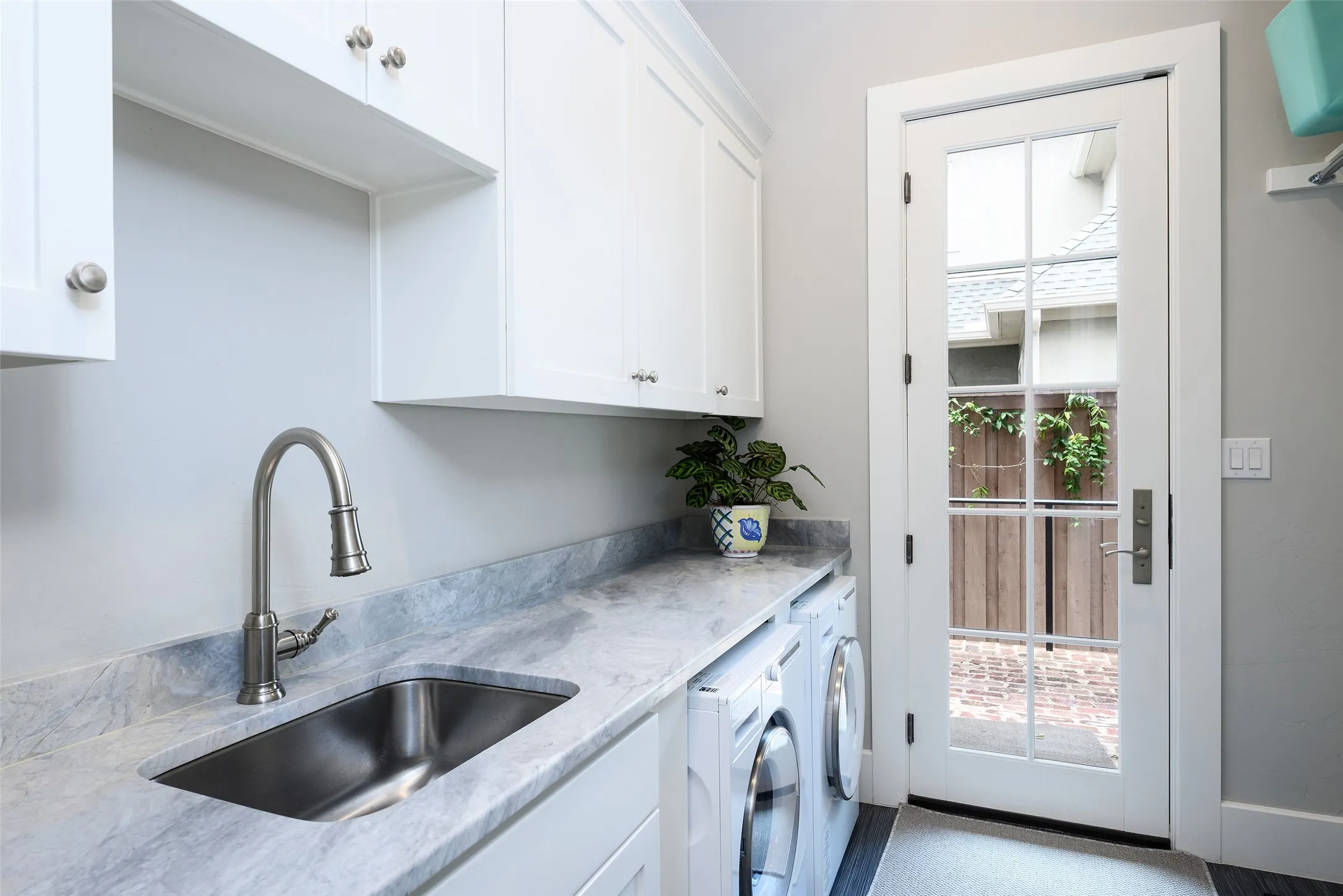 White cabinetry, undermount sink, stone countertop, brushed nickel faucet, and a glass-paned door
