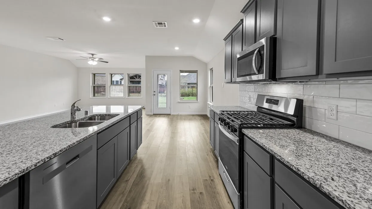 Modern kitchen featuring stainless steel appliances, granite countertops, and dark cabinetry