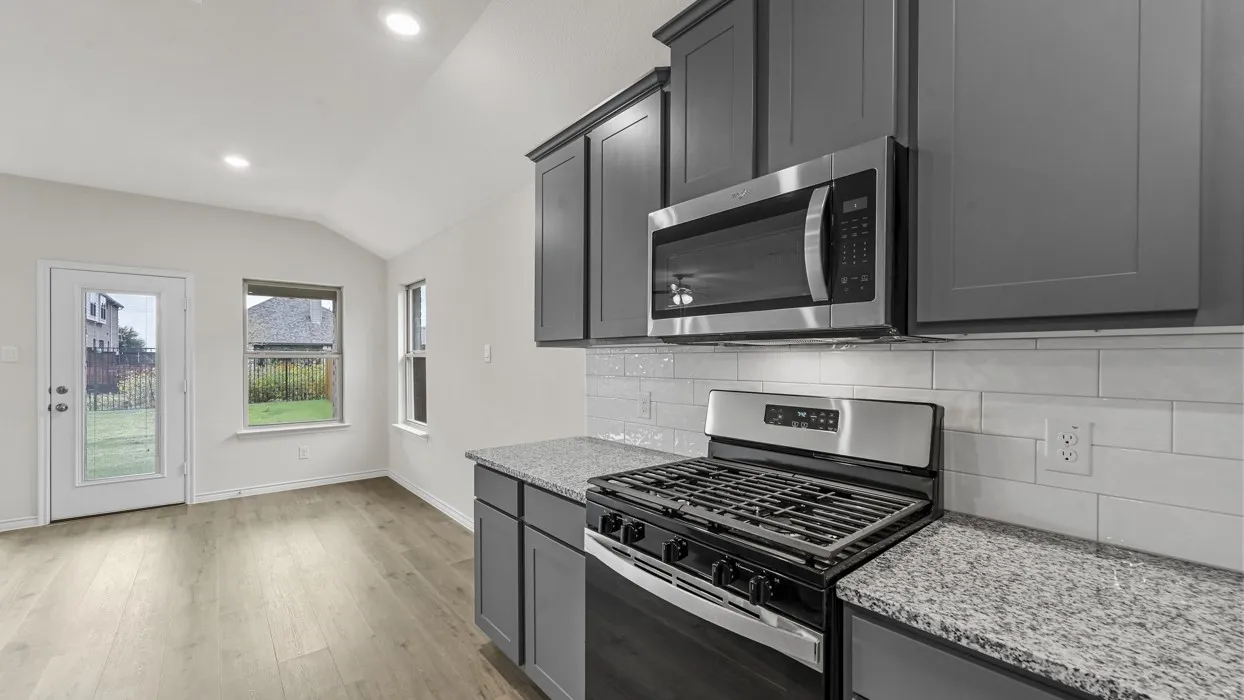 Kitchen featuring stainless steel appliances, granite-style countertops, gray cabinetry, and a subway tile backsplash