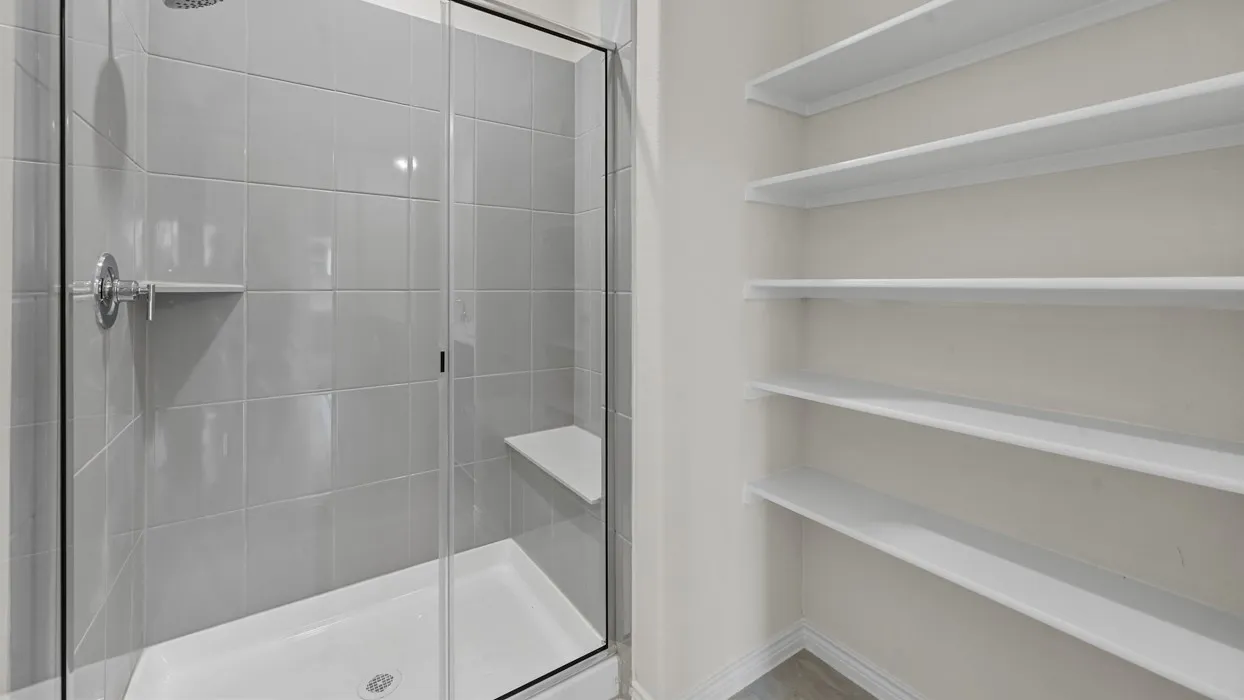 Glass-enclosed shower with a built-in bench and recessed shelf