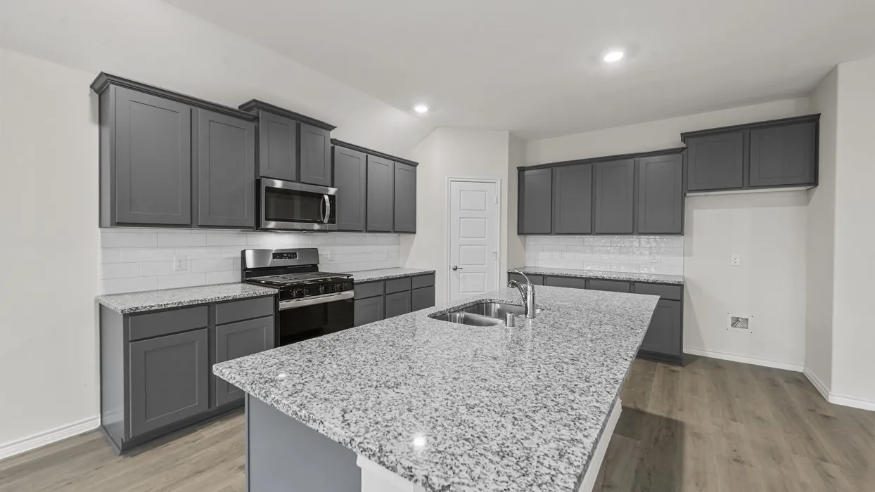Kitchen featuring an island with a double basin sink, gray cabinetry, light-toned countertops, stainless steel appliances, and wood-finish flooring