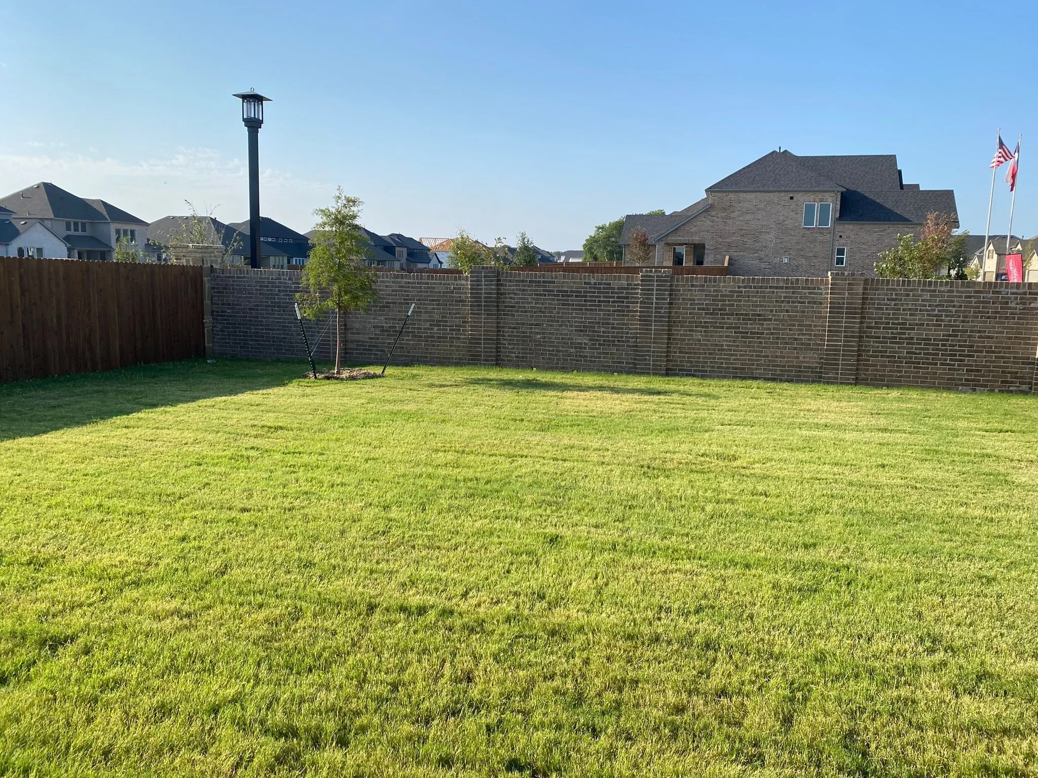 Expansive grass lawn with a full brick privacy wall and a wood fence