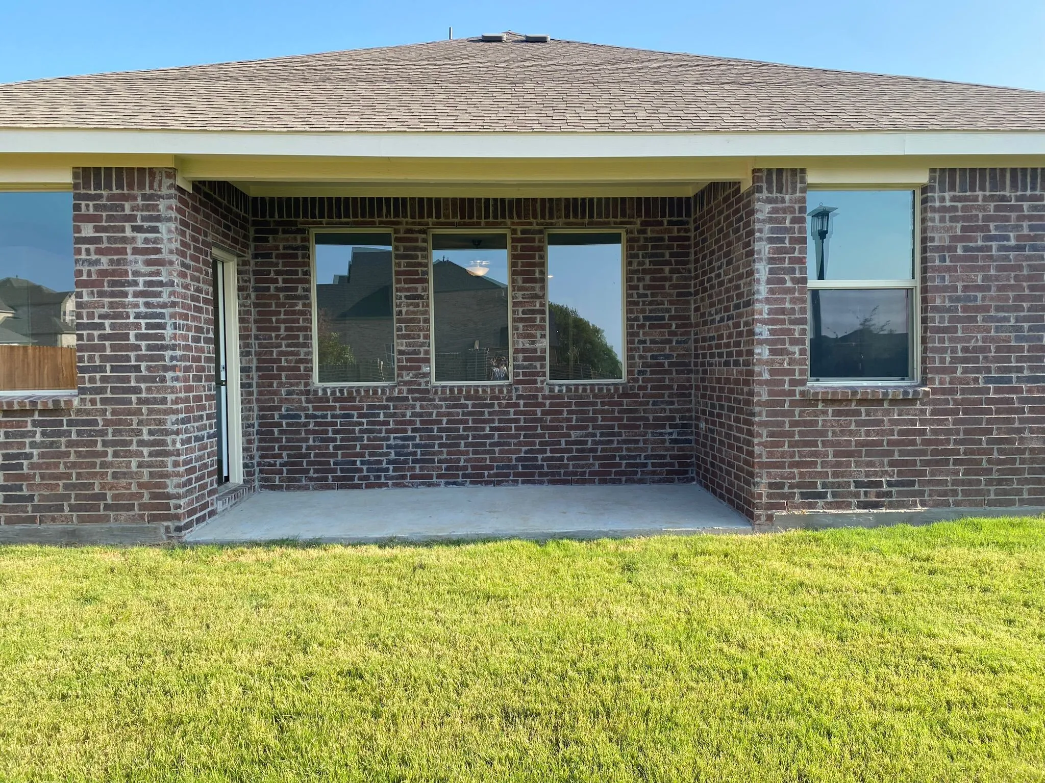 Brick exterior with a covered patio and a shingled roof